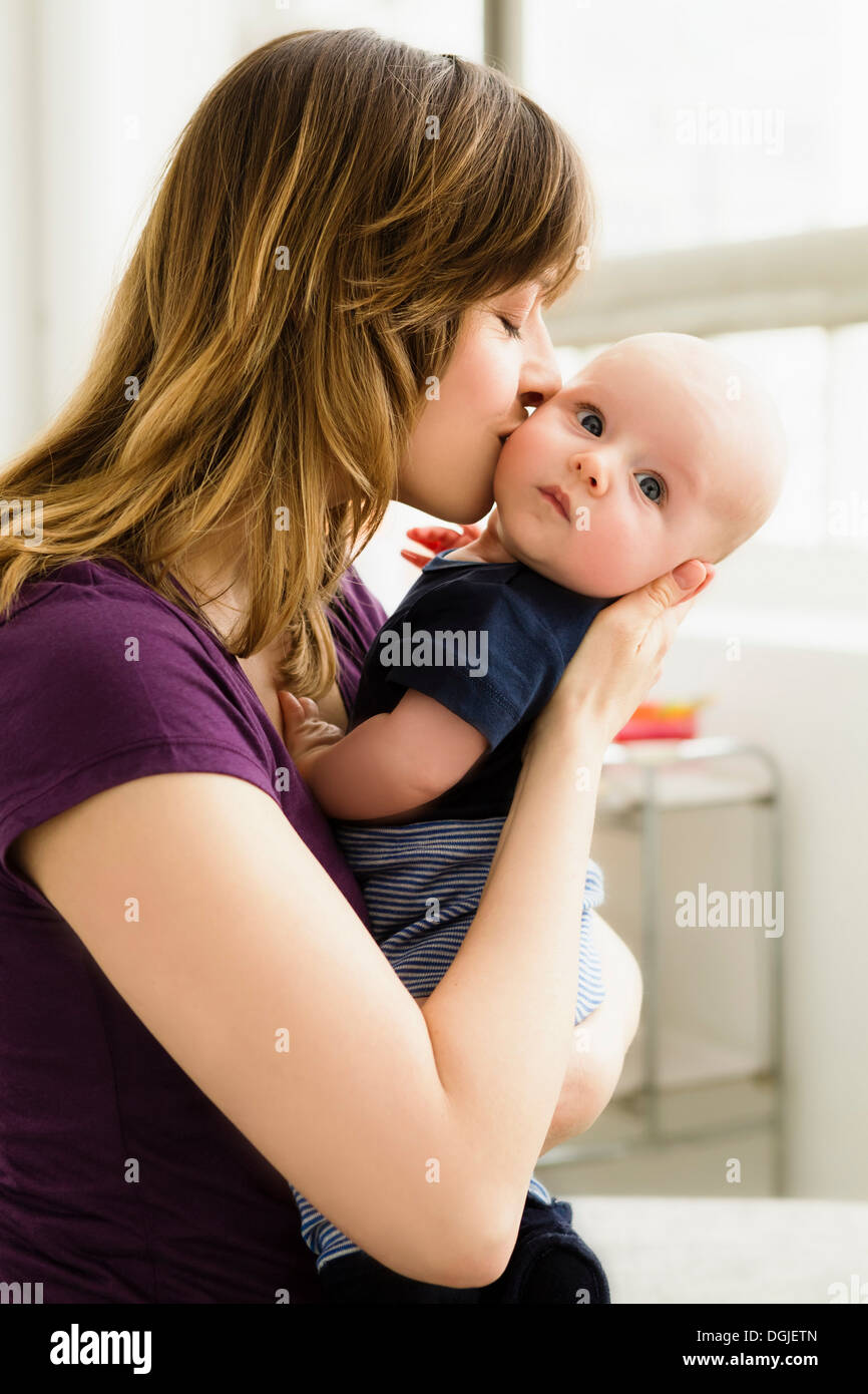 Madre kissing baby figlio sulla guancia Foto Stock