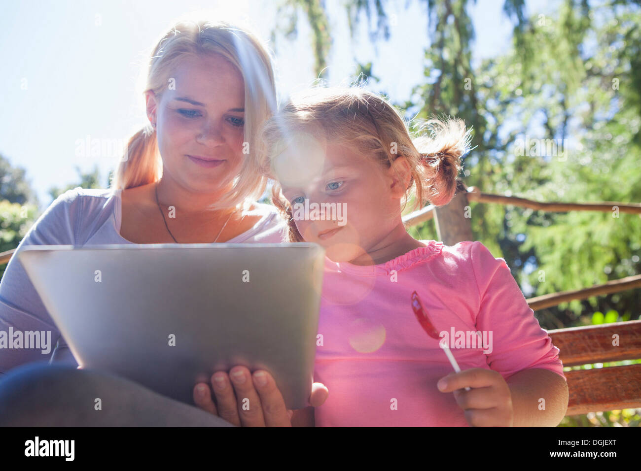 Madre utilizzando laptop, ragazza con lecca-lecca Foto Stock