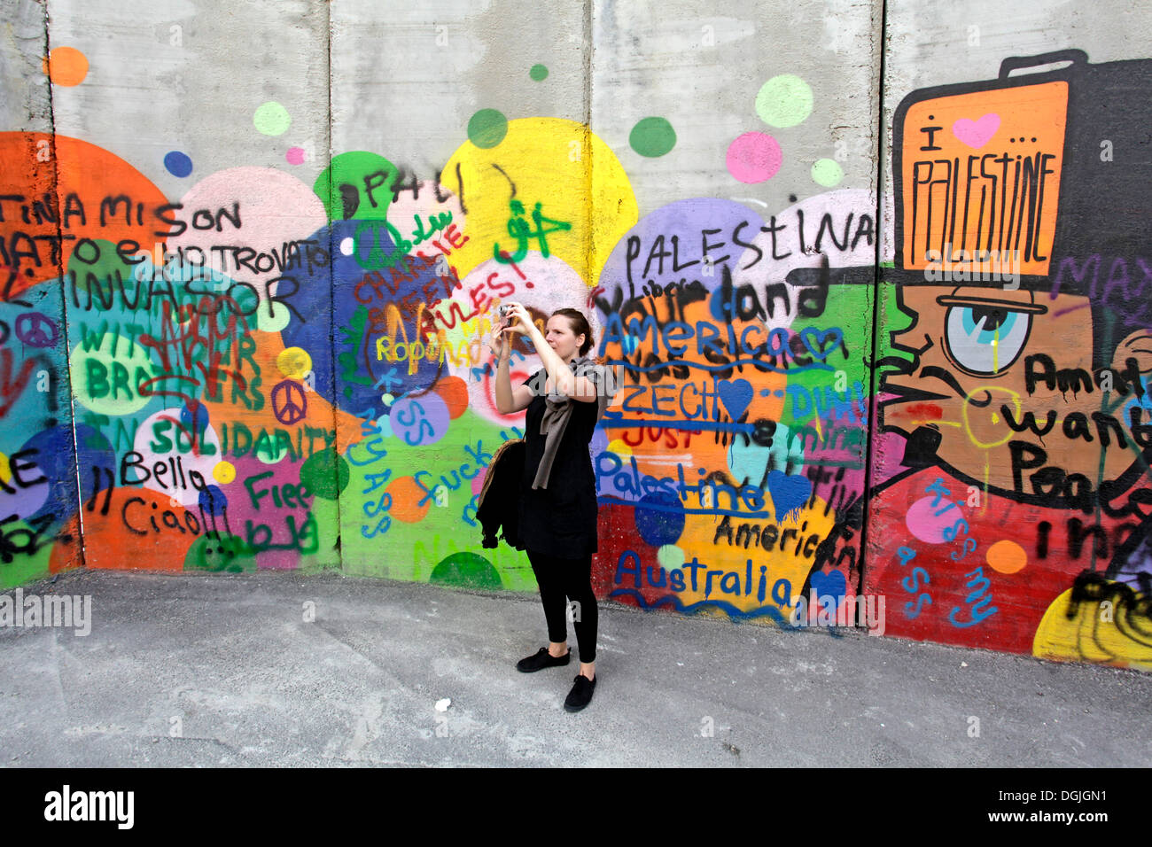 Donna di prendere una fotografia a un graffiti-coperti muro di difesa, palestinesi, tra Betlemme, in Cisgiordania e a Gerusalemme Foto Stock