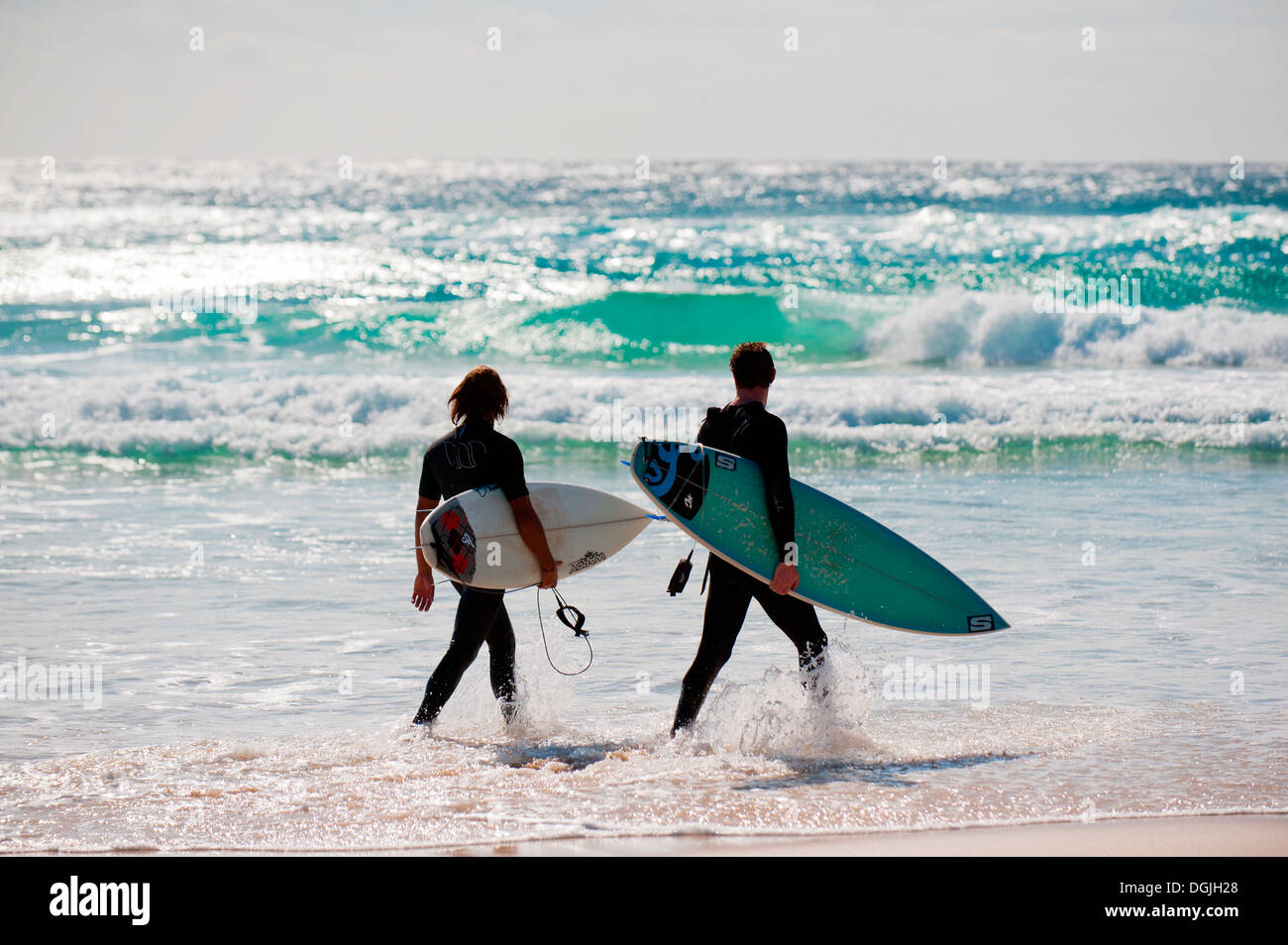 Surfers camminando lungo il cilindro sulla spiaggia di North Stradbroke Island nel Queensland. Foto Stock