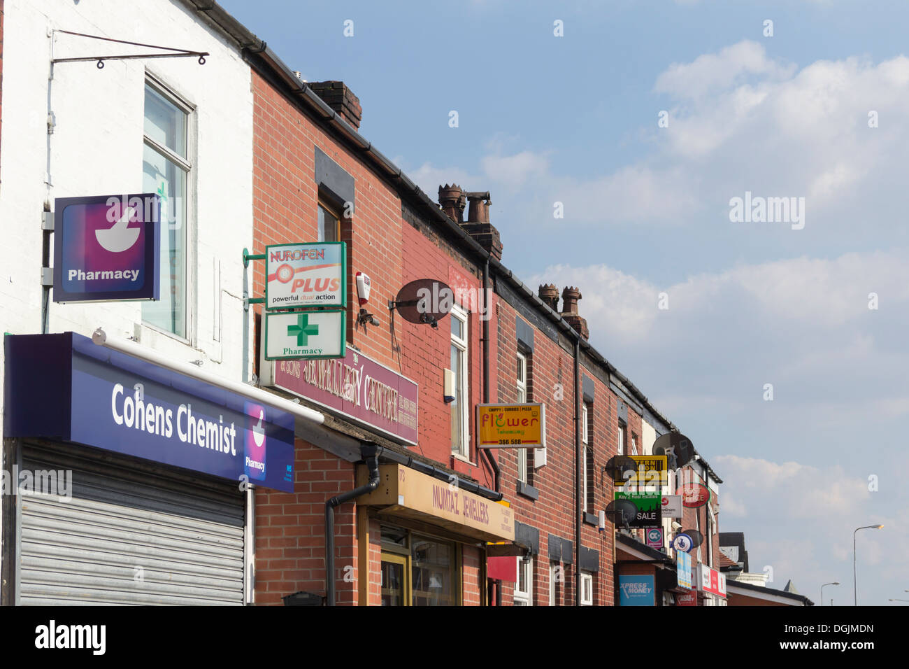 Una sfilata di piccoli negozi in Crescent Road, Bolton, Lancashire, ciascuno con segni sporgenti e da fasce la pubblicità dei loro affari. Foto Stock