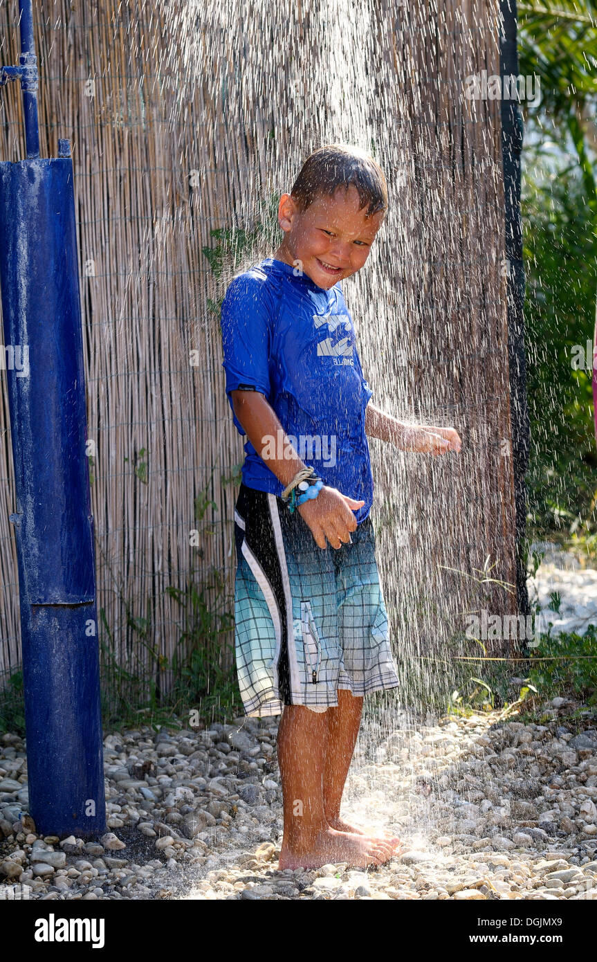 5-anno-vecchio ragazzo che indossa una maglietta blu in piedi sotto una doccia in giardino, Vassiliki, Lefkas, Grecia, Europa Foto Stock