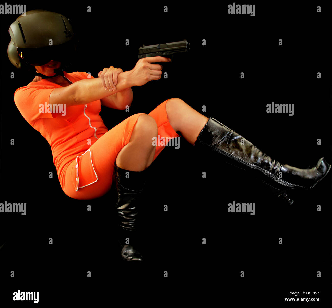 Donna che indossa una tuta arancione cadere all'indietro sparare una pistola Foto Stock