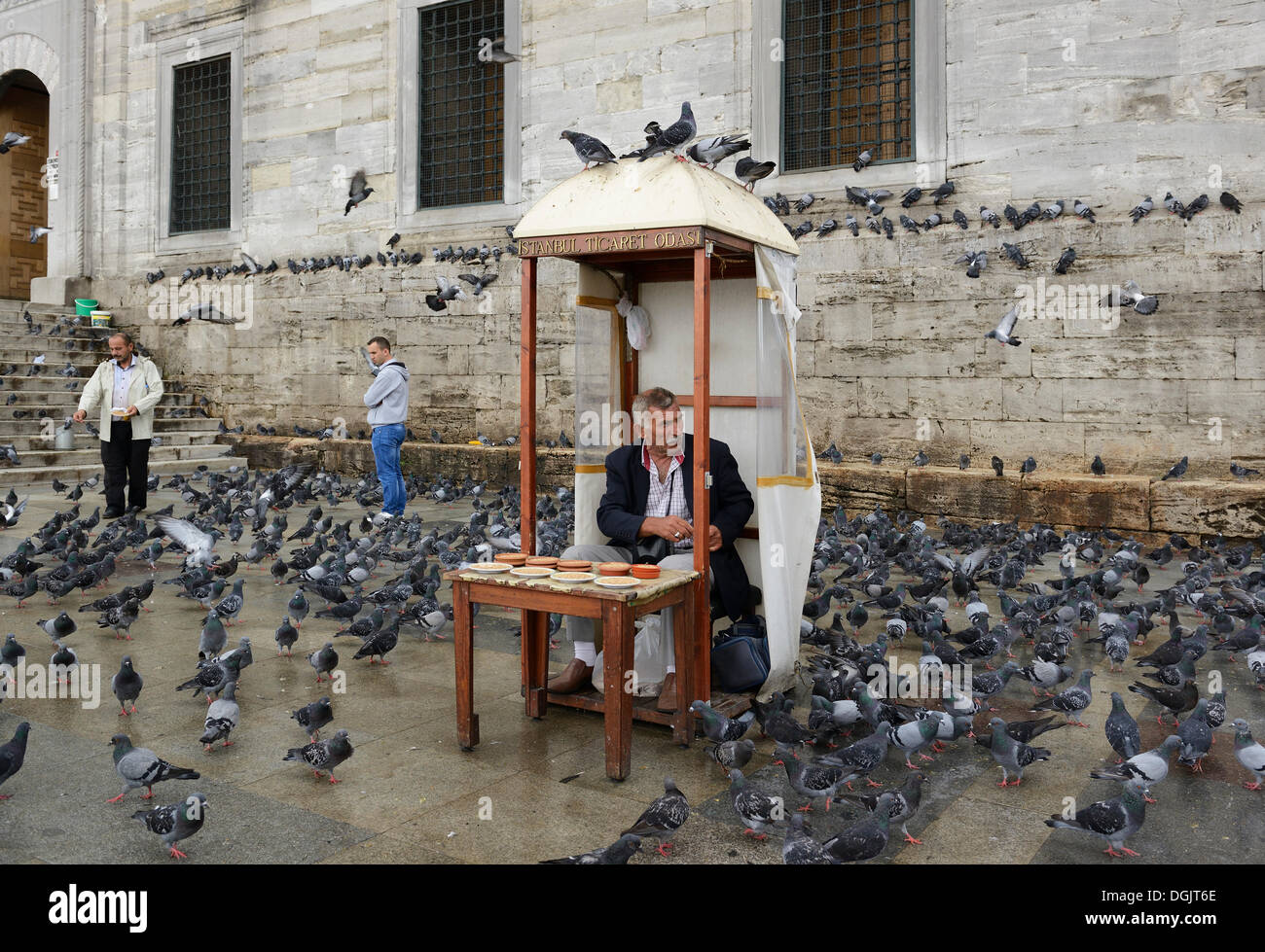 L'uomo uccello di vendita feed, circondato da piccioni, di fronte alla Yeni Cami o Nuova Moschea, Eminönü, Istanbul, lato europeo Foto Stock