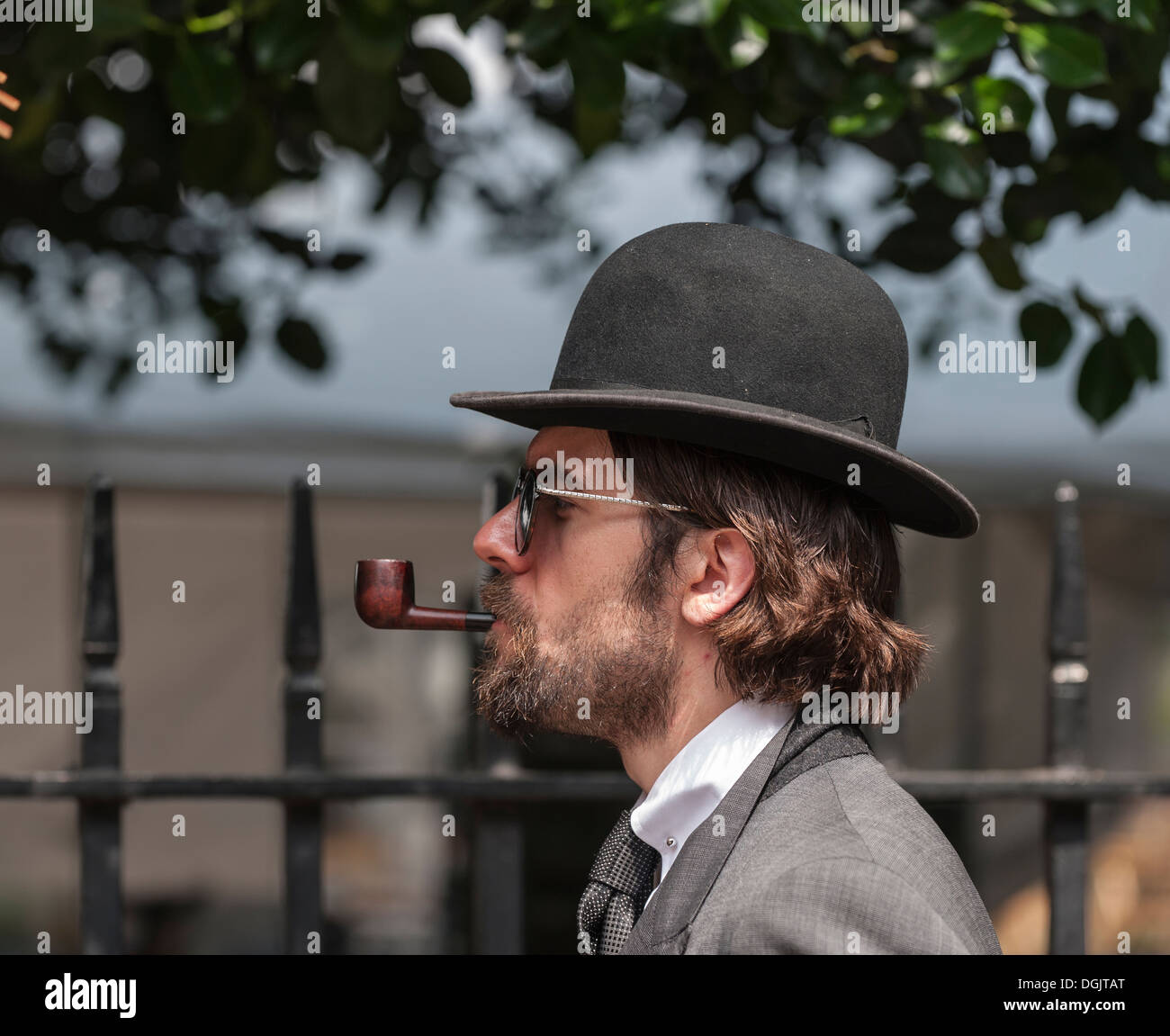 Un uomo che indossa un cappello bowler e fumare una tubazione in attesa per  l'inizio dell'Olimpiade Chap in Bedford Square Gardens Foto stock - Alamy