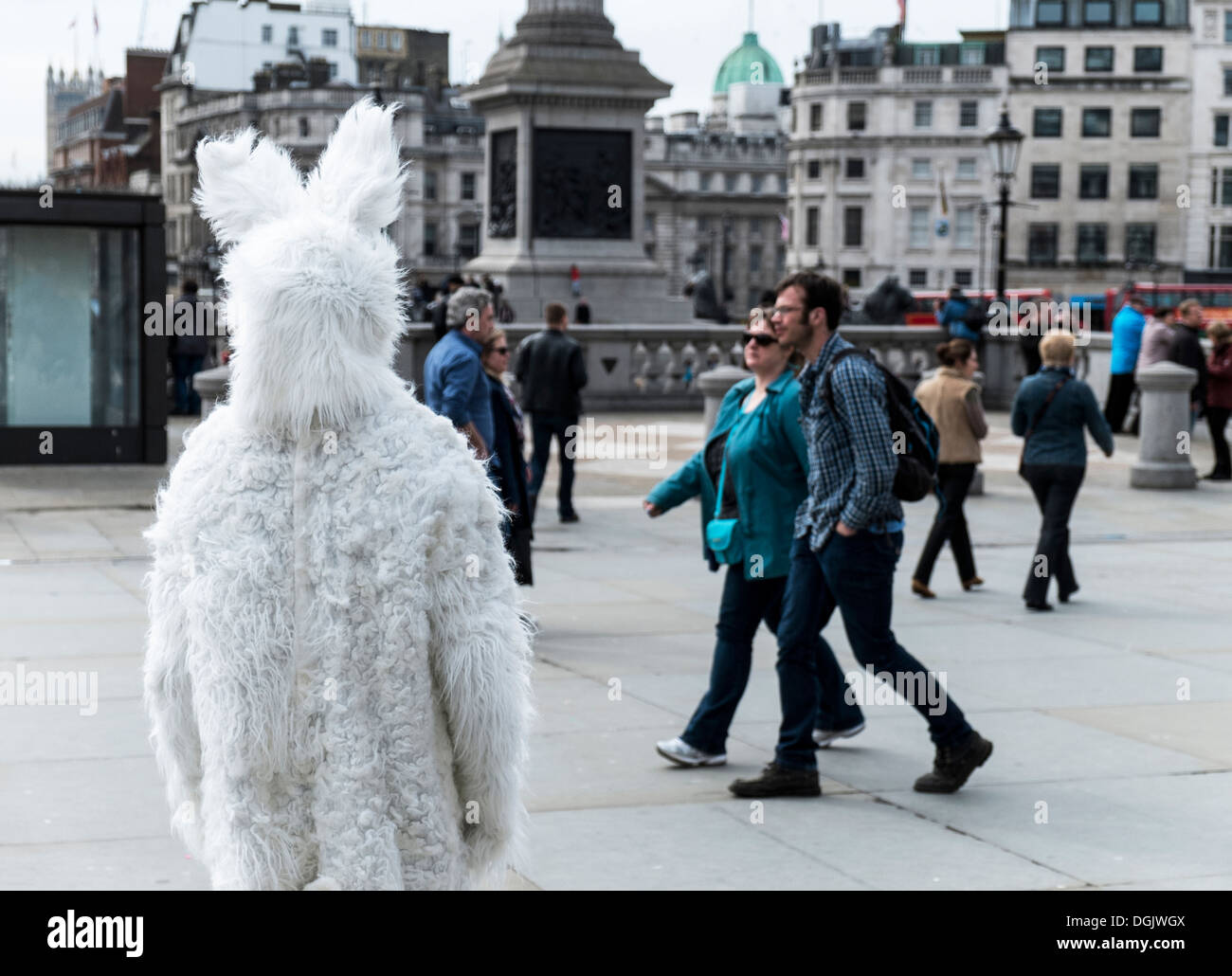 Un uomo vestito come un coniglio bianco viene ignorato dal popolo in Trafalgar Square. Foto Stock