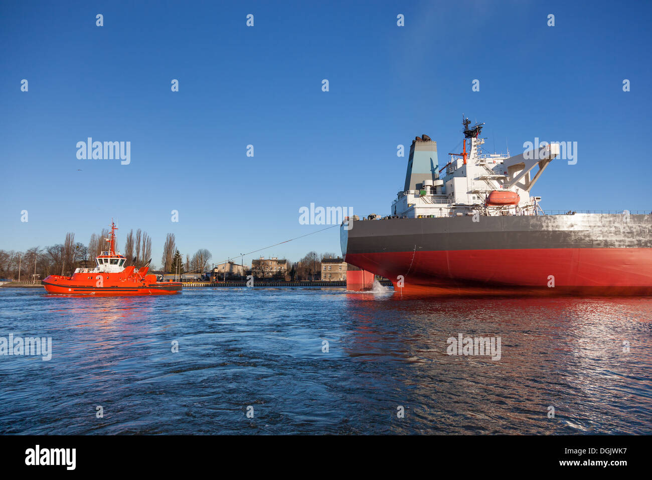 Un rimorchiatore arancione assistere una grande petroliera. Foto Stock