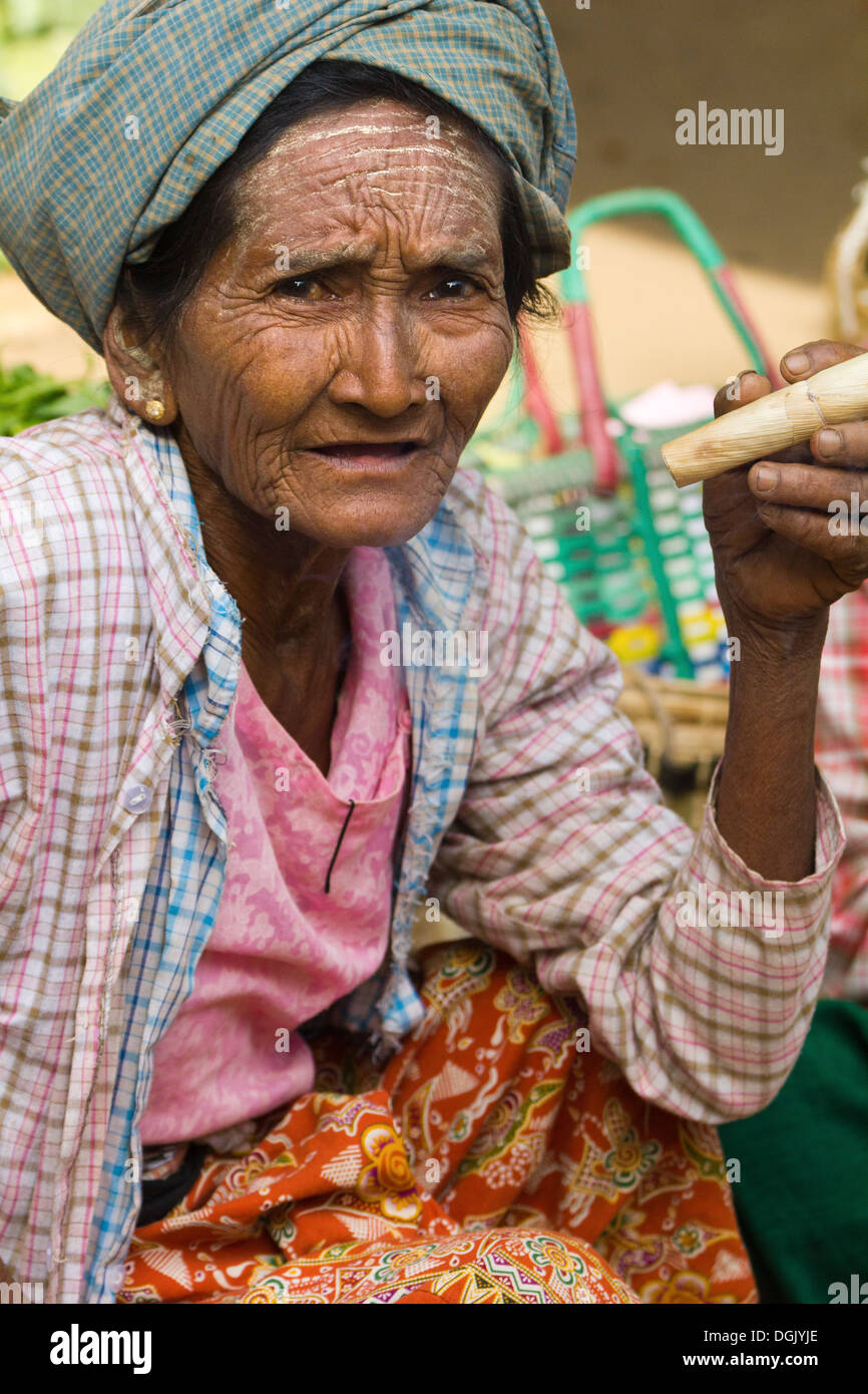 Una vecchia donna di fumare un sigaro di scandaloso in Nyaung oo mercato in Bagan in Myanmar. Foto Stock