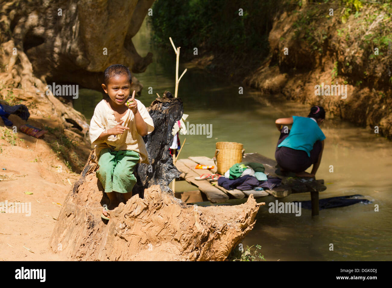 Un giovane ragazzo da un flusso mentre sua madre fa il lavaggio in Inn Thein Village. Foto Stock
