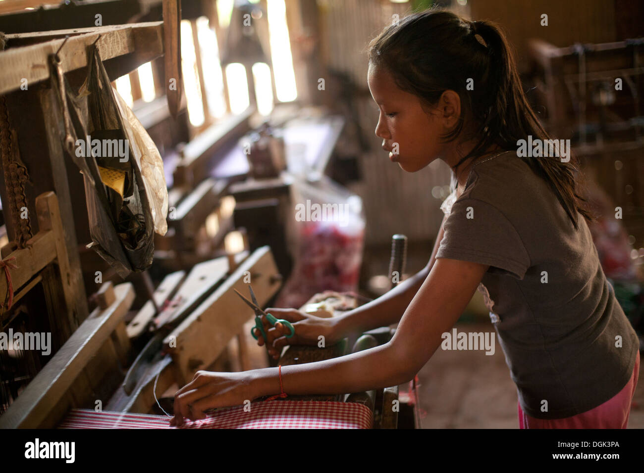 Una giovane ragazza lavora in un villaggio fabbrica tessile al di fuori di Phnom Penh Cambogia. Foto © Dennis Drenner 2013. Foto Stock
