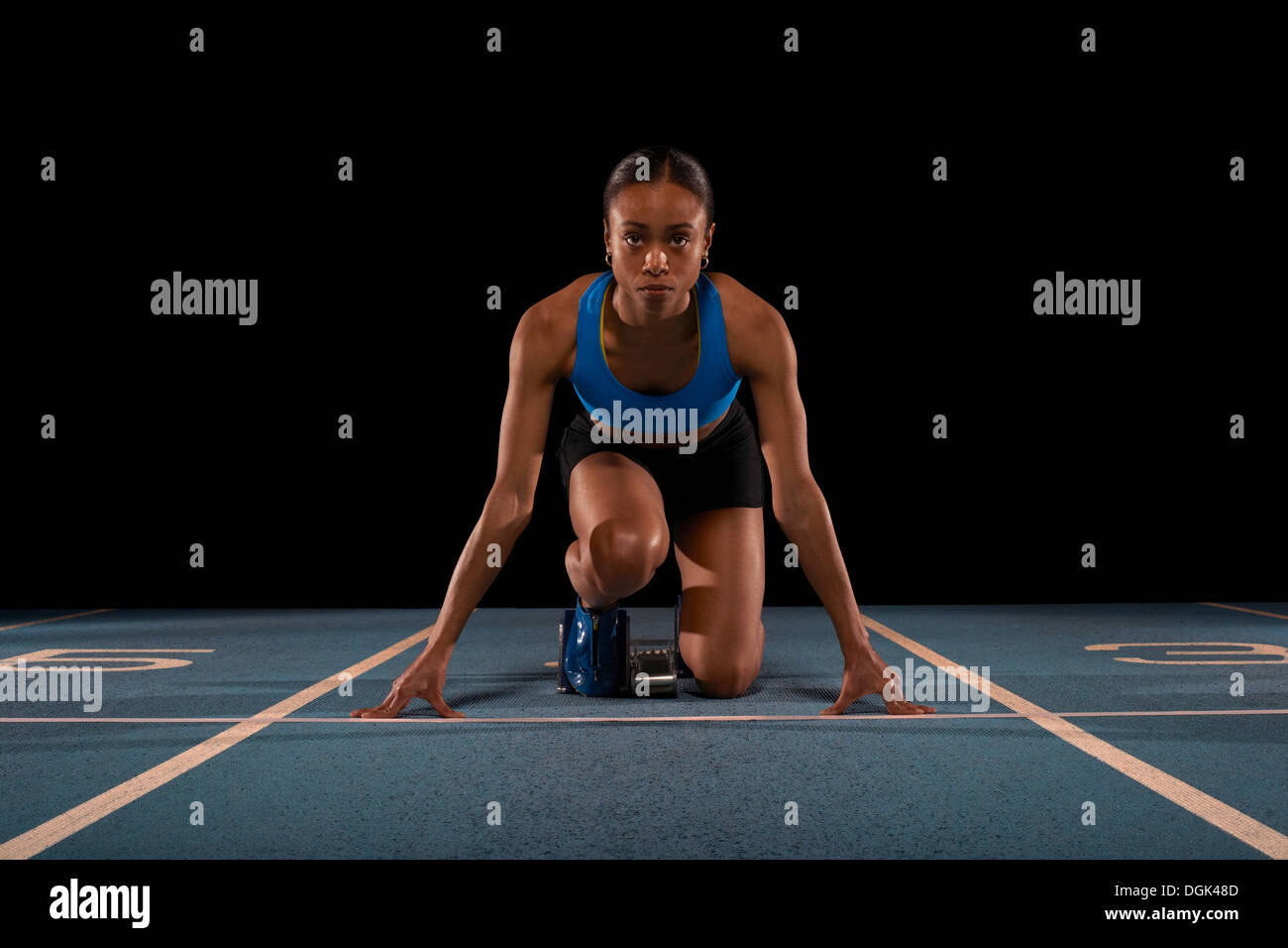 Giovane atleta femminile sui blocchi di partenza Foto Stock