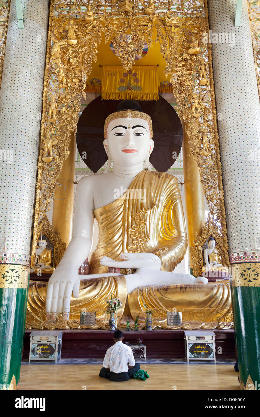 Un uomo che prega al Grande Buddha seduto alla Shwedagon pagoda in Yangon in Myanmar. Foto Stock