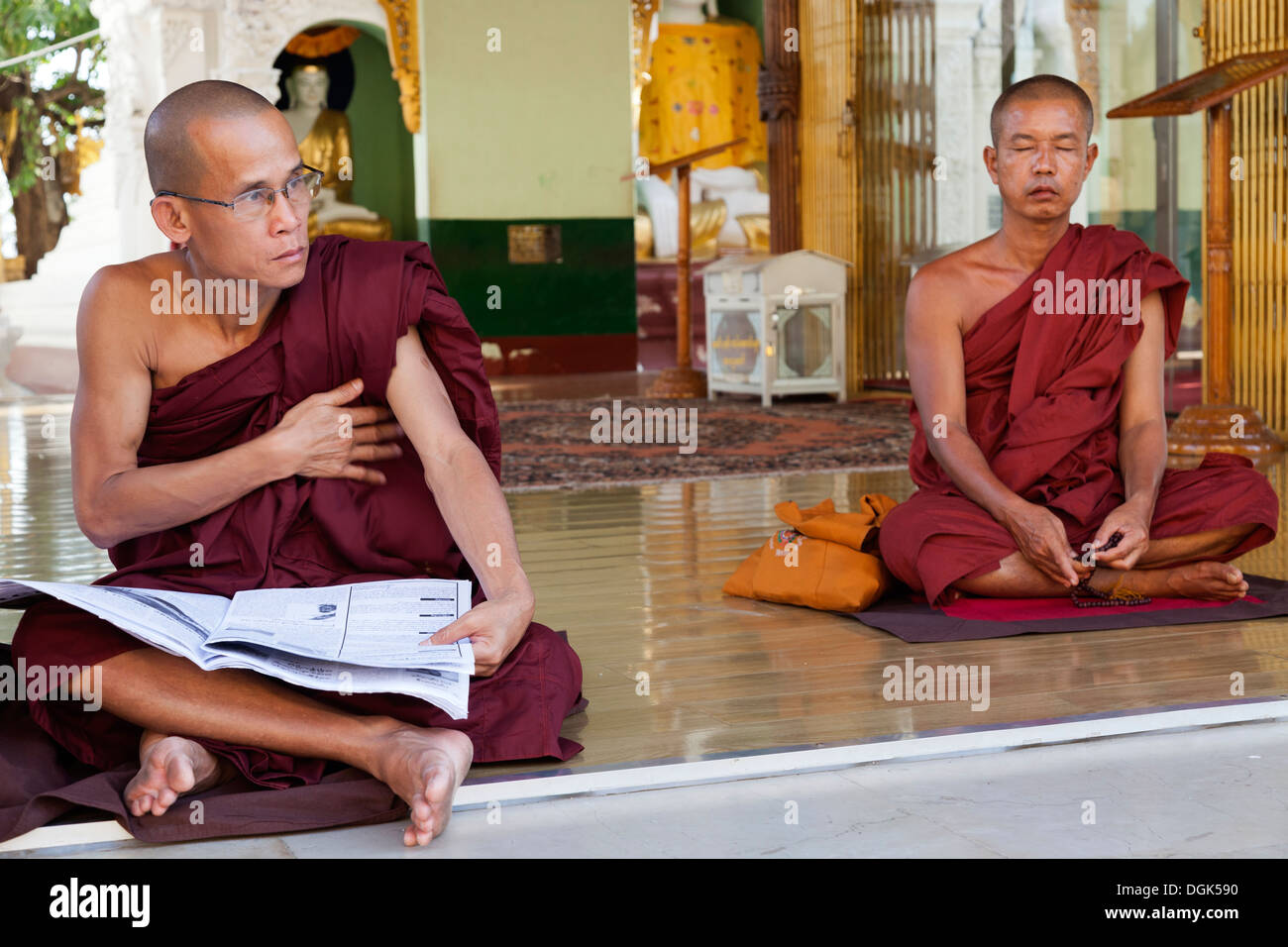 Due monaci con una meditazione e una lettura di un quotidiano a la Shwedagon pagoda in Yangon in Myanmar. Foto Stock