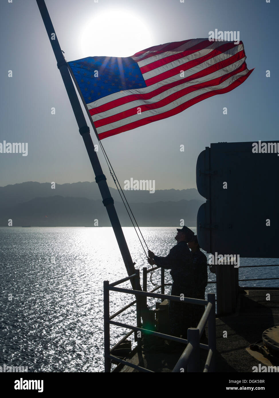 I marinai attaccato all'assalto anfibio nave USS Kearsarge (LHD 3) abbassare il ensign nazionale dopo ricevendo in corso. Kearsarge è l'ammiraglia per il Kearsarge Amphibious pronto il gruppo e con la avviato 26 Marine Expeditionary Unit, è distribuito i Foto Stock