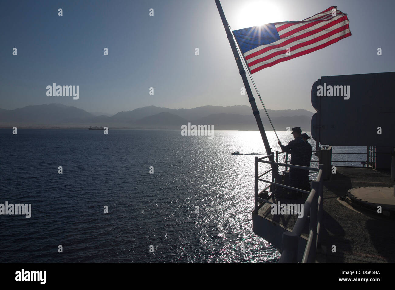 I marinai attaccato all'assalto anfibio nave USS Kearsarge (LHD 3) abbassare il ensign nazionale dopo ricevendo in corso. Kearsar Foto Stock