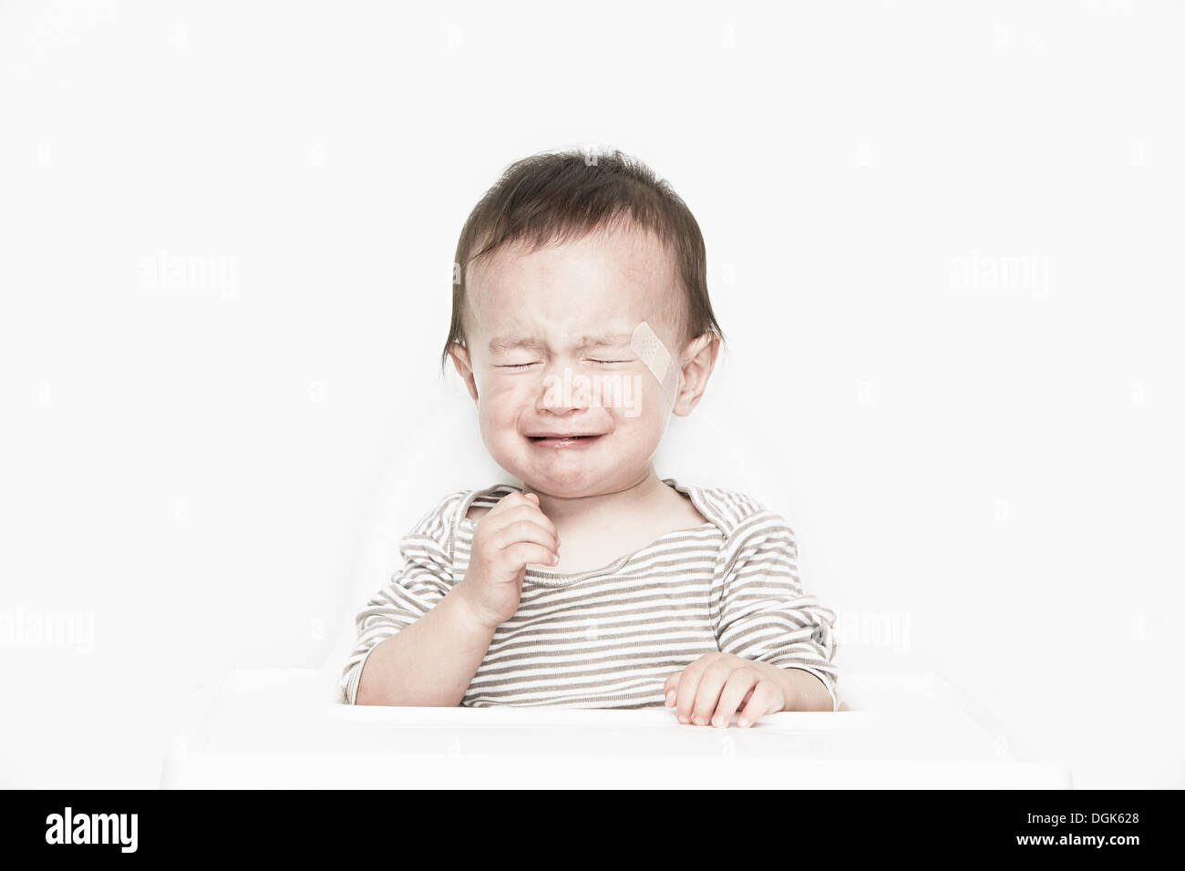 Baby boy con cerotto adesivo sulla faccia che piange Foto Stock