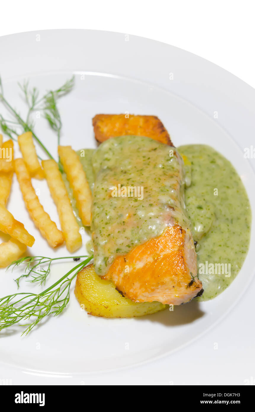 Salmone arrosto servita con salsa verde e patatine fritte sulla piastra bianca Foto Stock