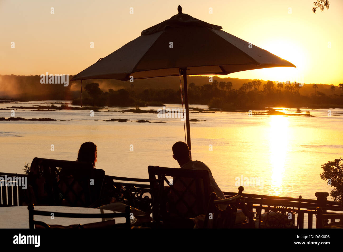 Una giovane coppia in vacanza a guardare il tramonto sul fiume Zambesi e vicino a Victoria Falls, Royal Livingstone Hotel, Zambia Africa Foto Stock