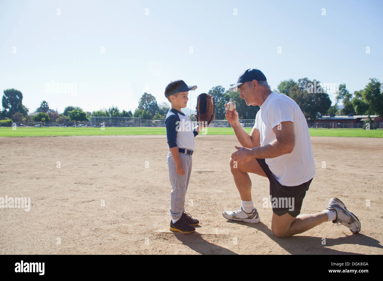 Uomo che parla al nipote sul campo di baseball Foto Stock
