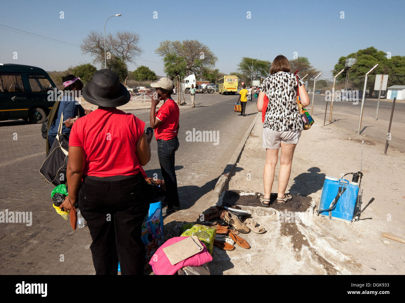 Un turista stepping nel disinfettante per evitare di afta epizootica presso il posto di frontiera di inserire lo Zimbabwe dallo Zambia, Africa Foto Stock