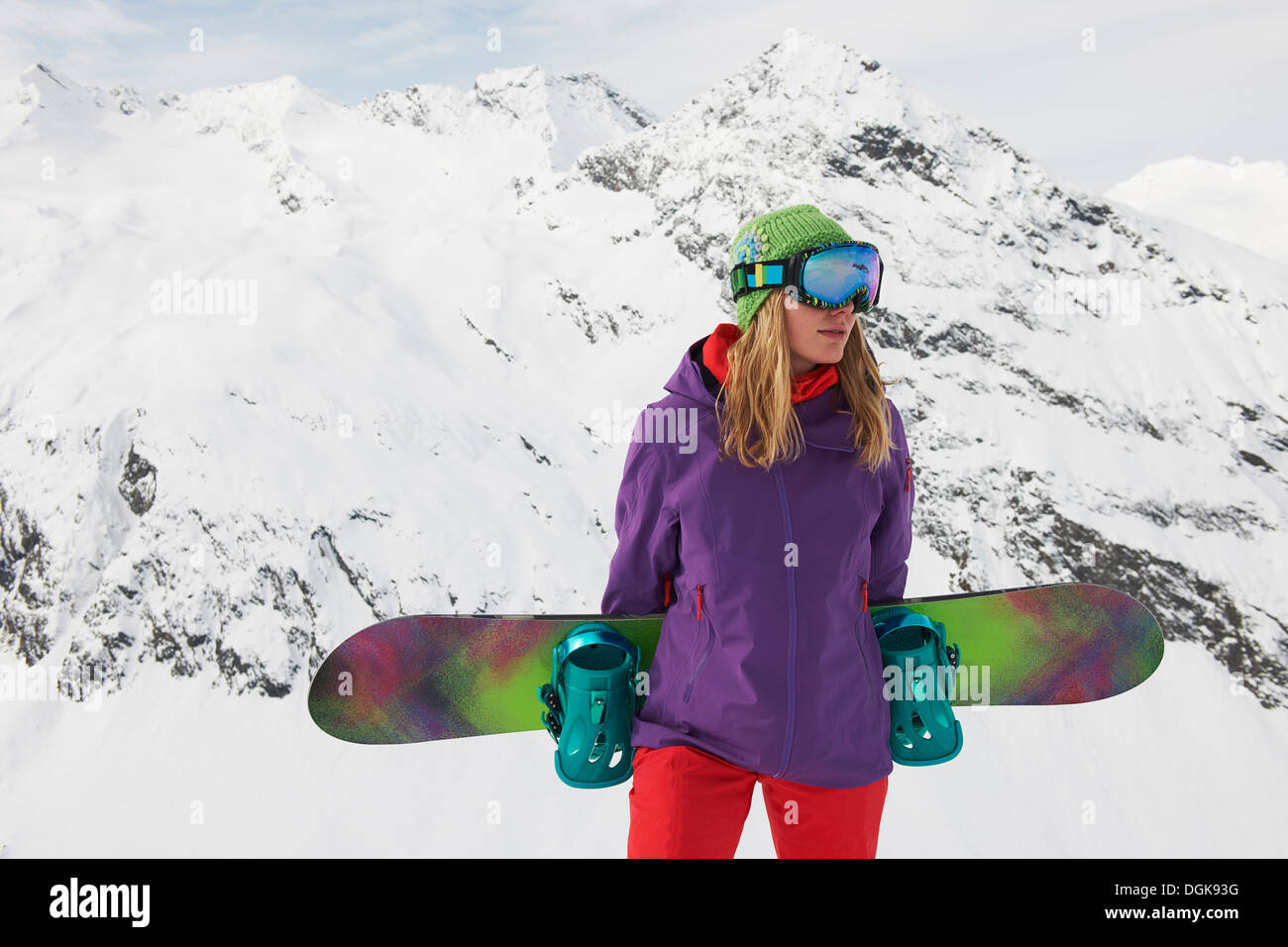 Giovane donna holding snowboard alla cima della montagna Foto Stock
