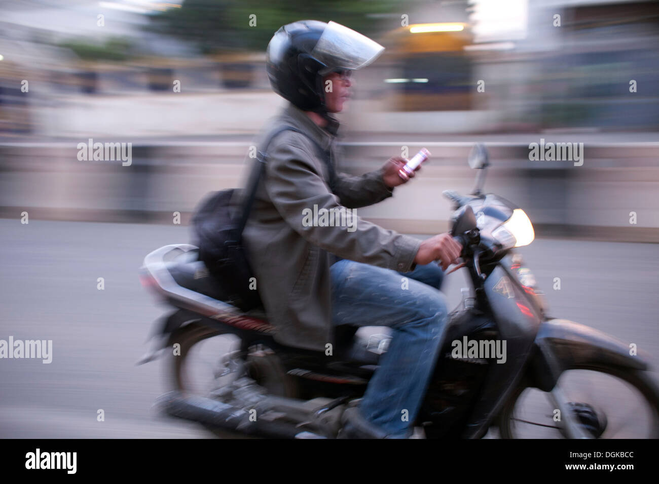 Un motociclista controlla il suo smartphone in Phnom Penh Cambogia. Foto © Dennis Drenner 2013. Foto Stock