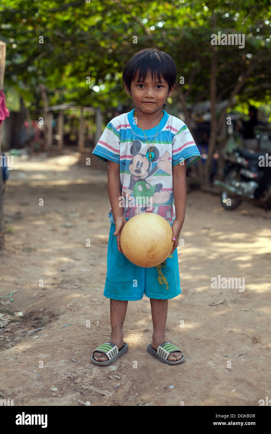 Ritratto di un giovane ragazzo con una palla in un piccolo villaggio fuori di Phnom Penh Cambogia. Foto © Dennis Drenner 2013. Foto Stock