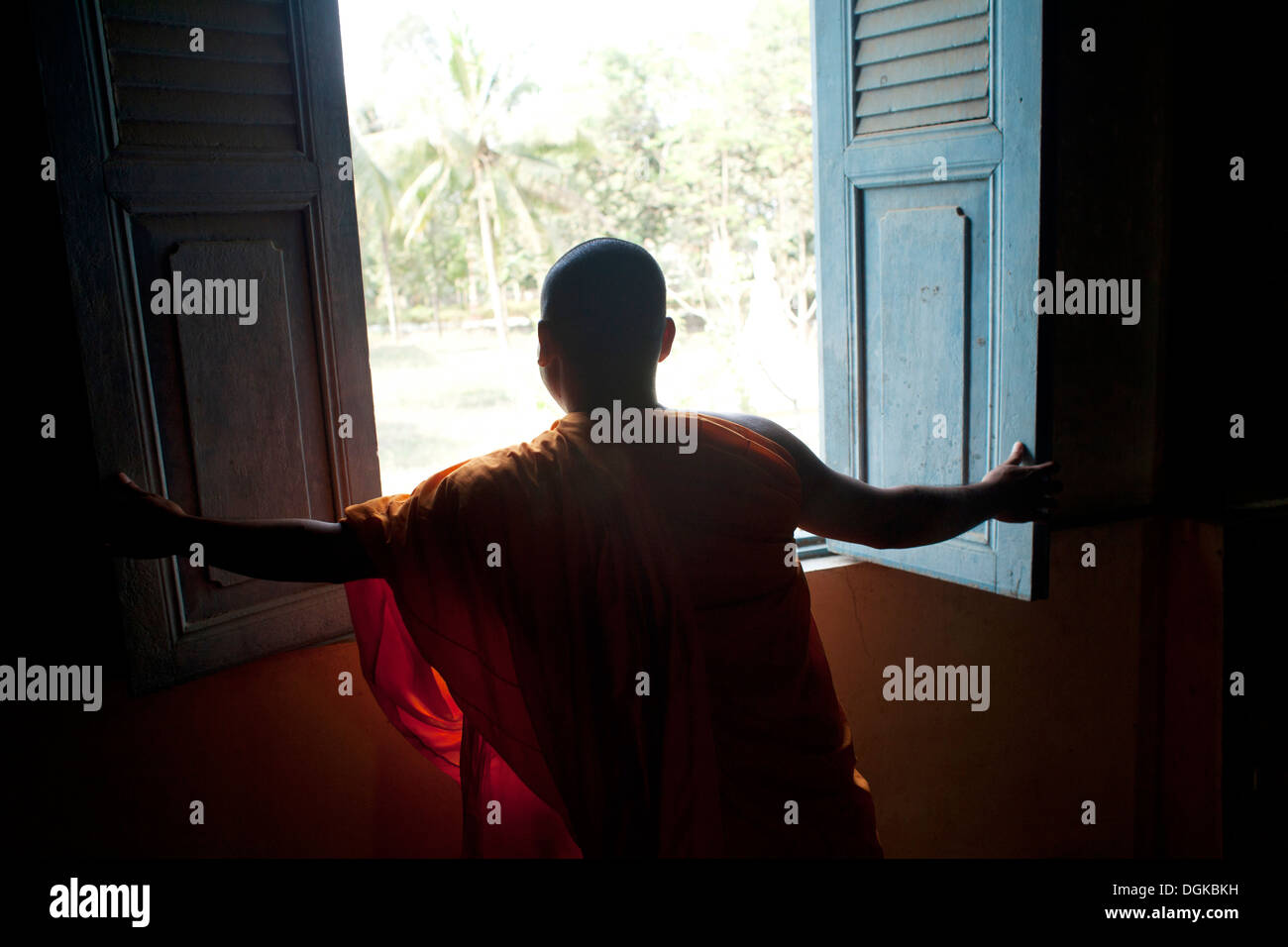 Un monaco si apre una finestra in un piccolo villaggio fuori del tempio di Phnom Penh Cambogia. Foto © Dennis Drenner 2013. Foto Stock