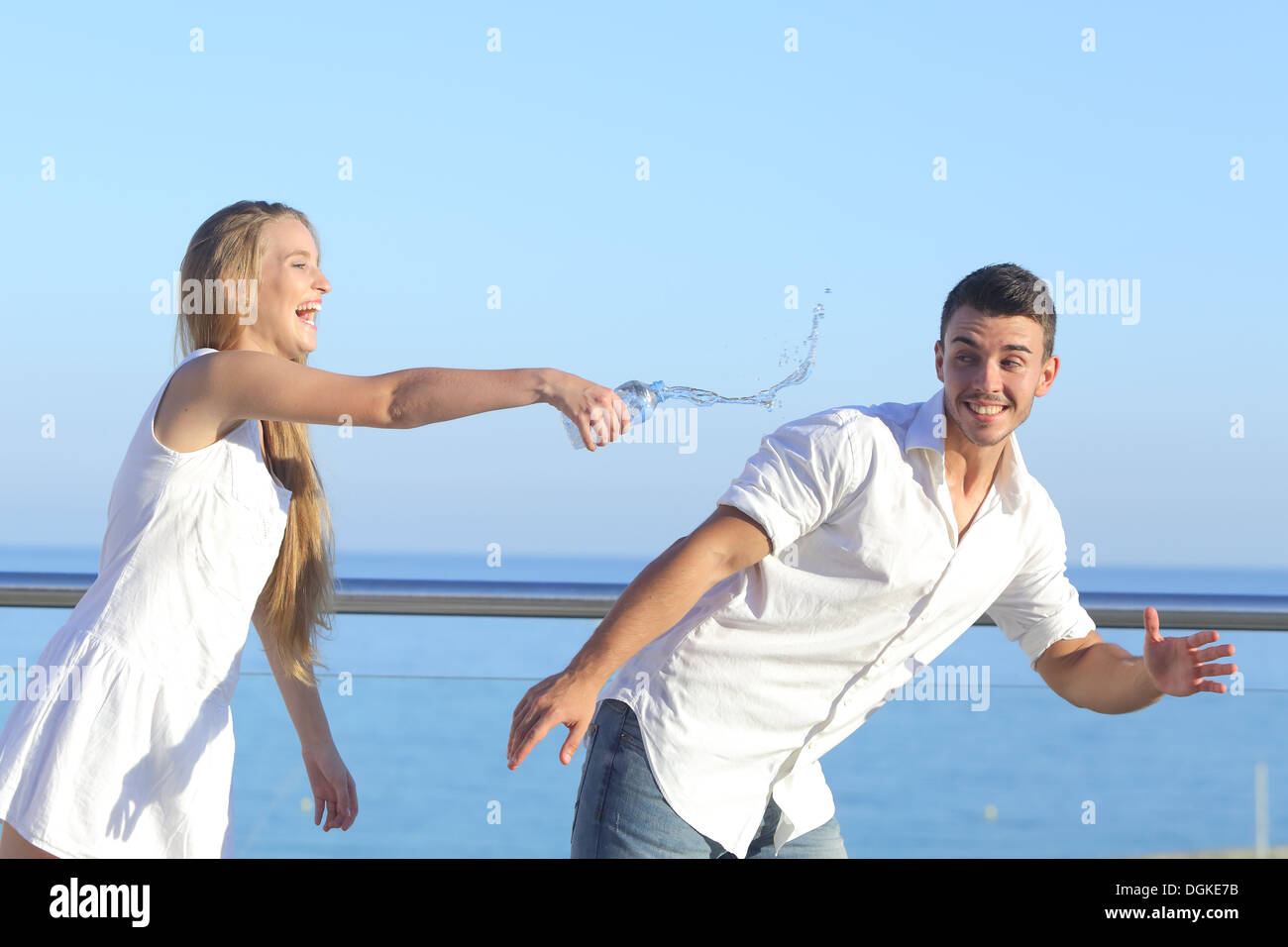Donna di gettare acqua per il suo fidanzato con il cielo in background Foto Stock
