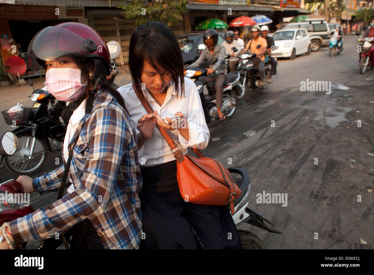 Una giovane donna testo dal retro di una moto in Phnom Penh Cambogia. Foto © Dennis Drenner 2013. Foto Stock