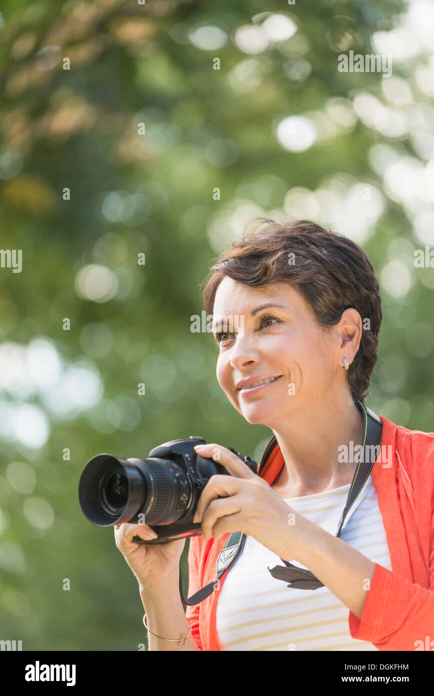 Donna matura tenere la fotocamera in posizione di parcheggio Foto Stock