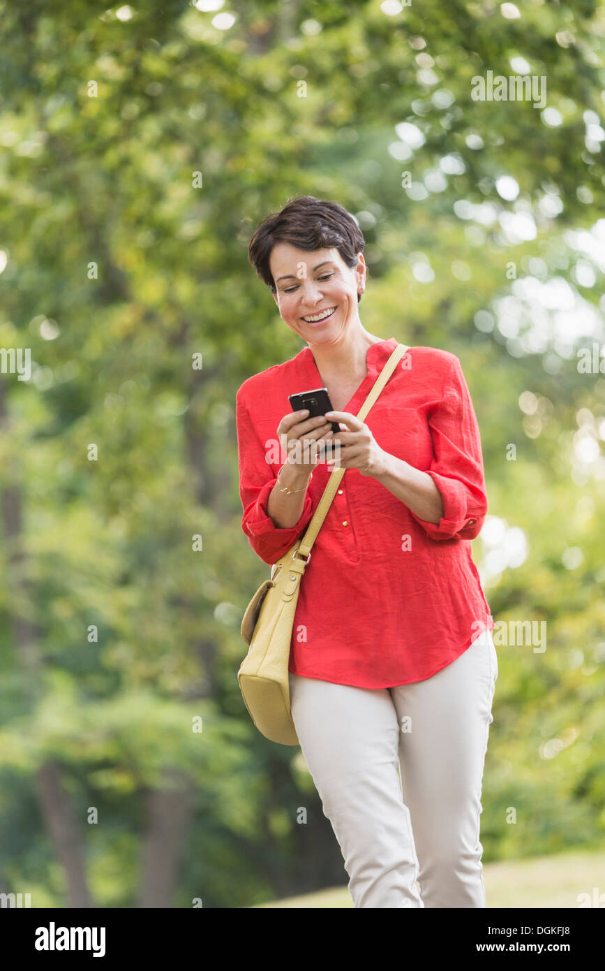 Donna matura per la messaggistica di testo in posizione di parcheggio Foto Stock