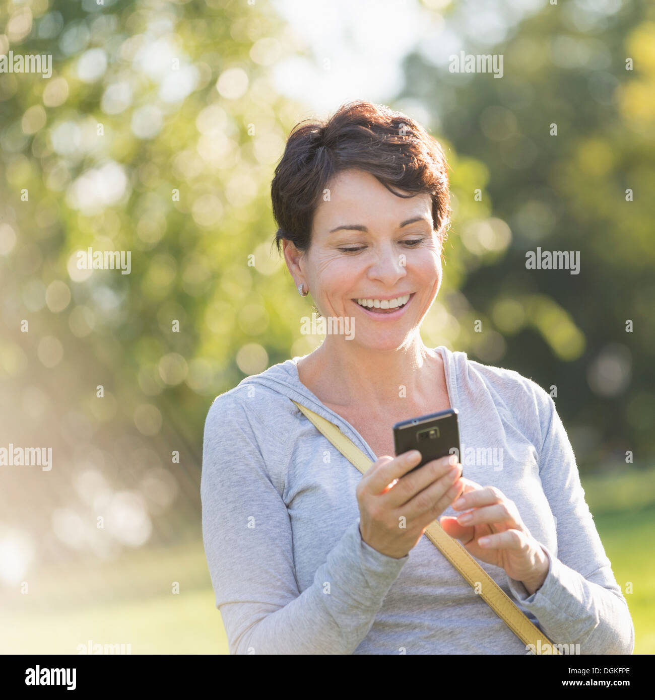 Donna matura per la messaggistica di testo all'aperto Foto Stock