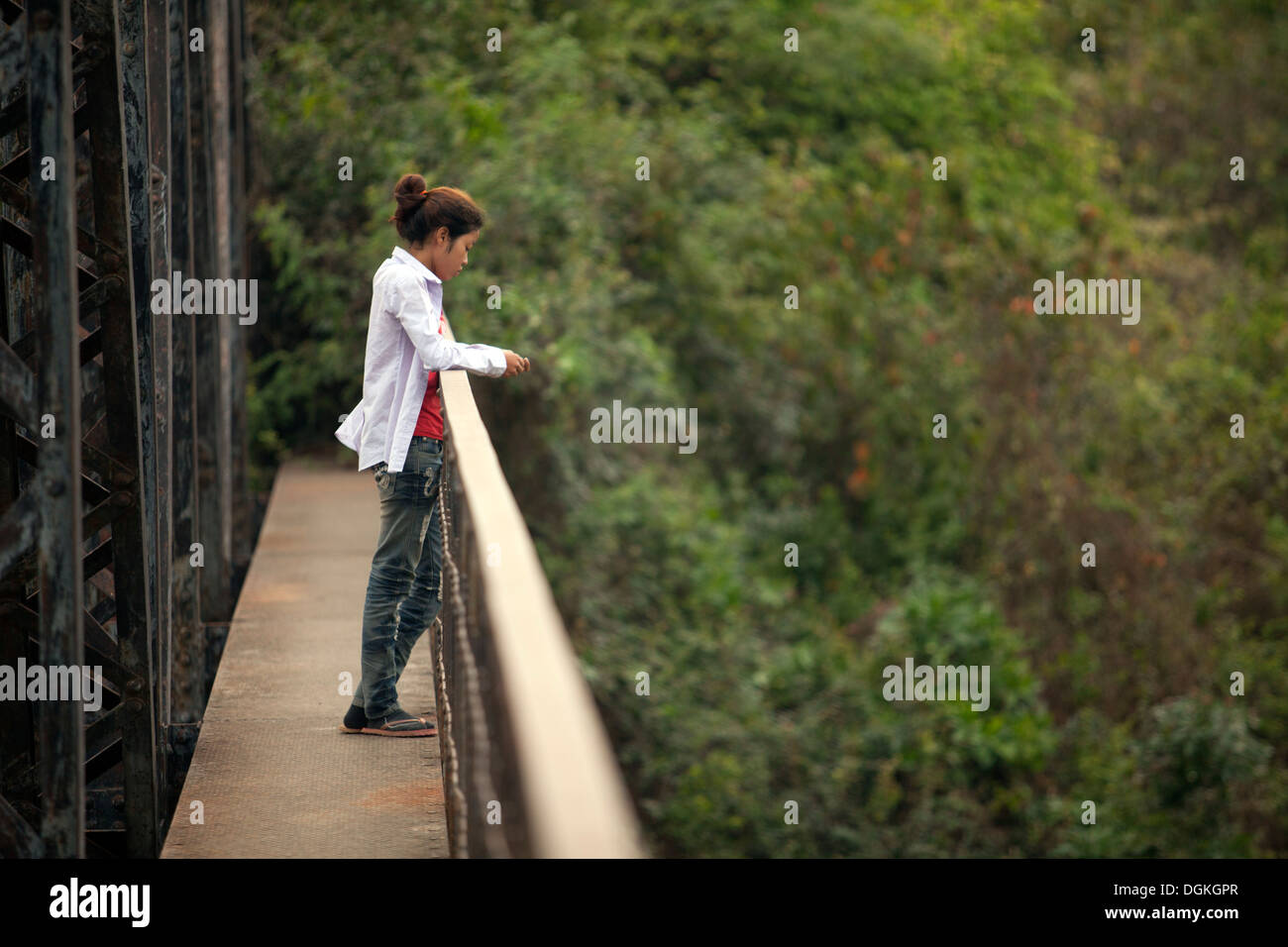 Una giovane donna guarda attentamente da un ponte in prossimità di Battambang, Cambogia. Foto © Dennis Drenner 2013. Foto Stock