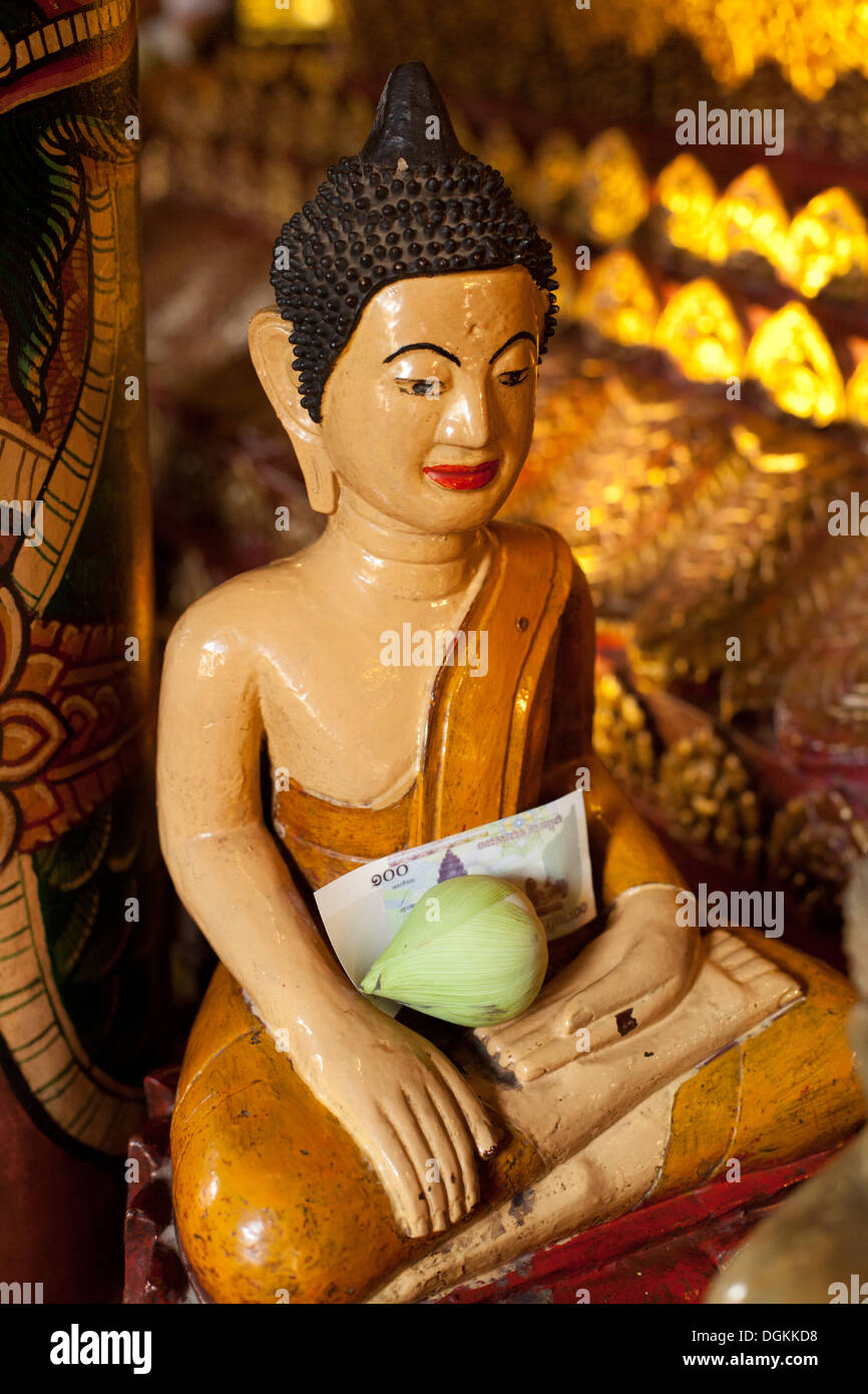 Statua del Buddha con offerte al Wat Phnom tempio Phnom Penh Cambogia. Foto © Dennis Drenner 2013. Foto Stock