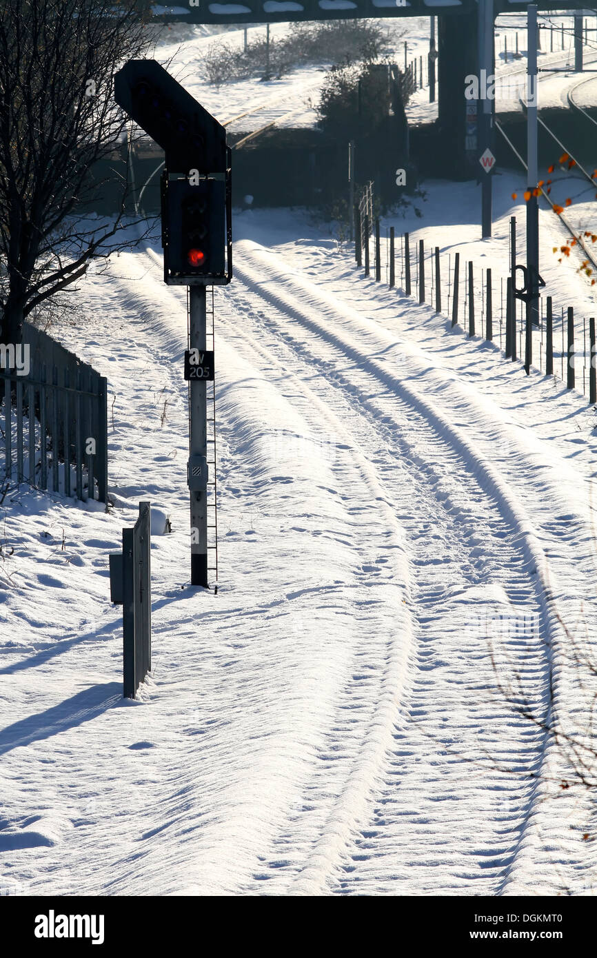 La curvatura delle linee ferroviarie completamente coperto di neve accanto a un segnale rosso. Foto Stock