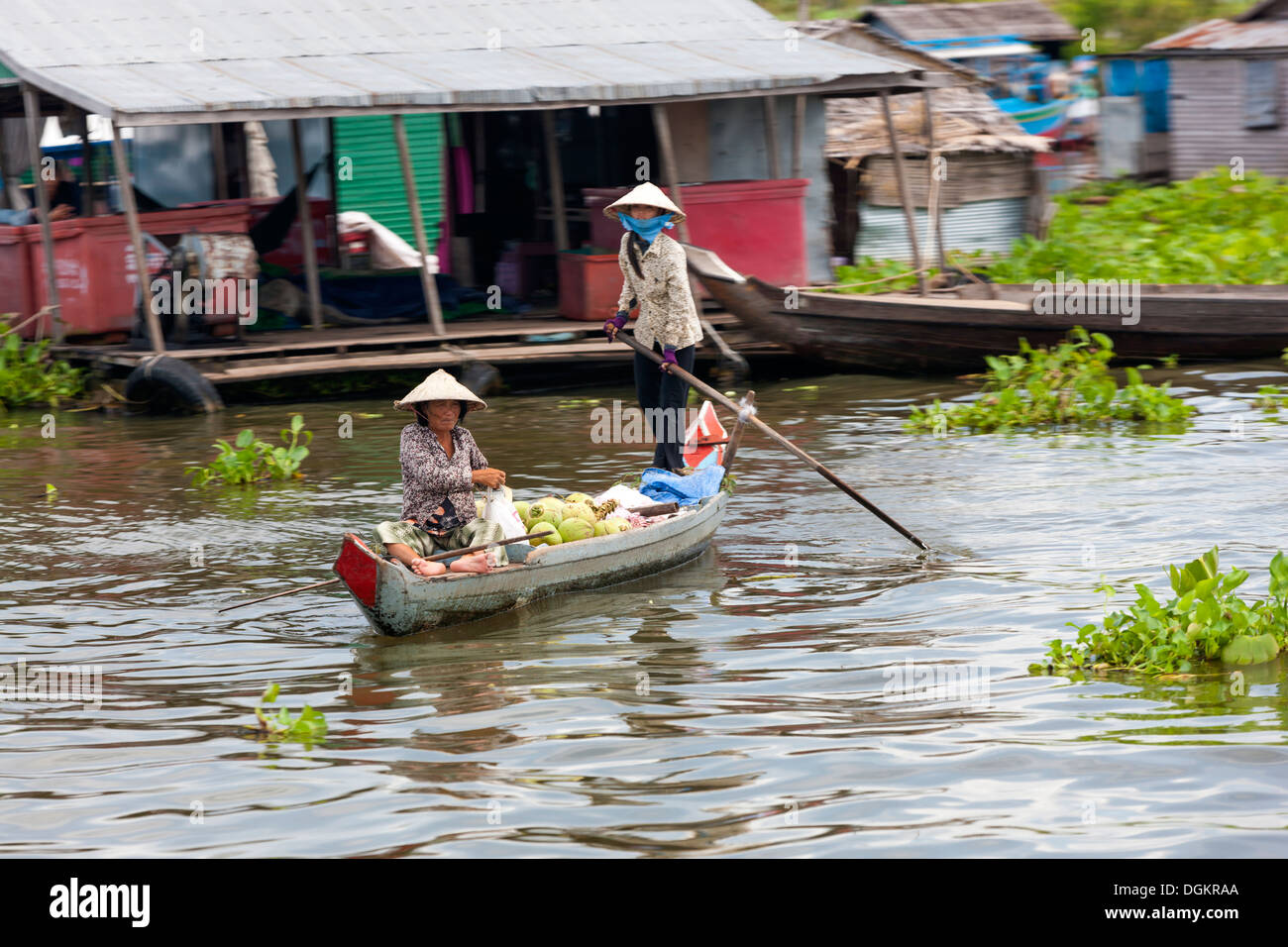 Una donna che aziona la sua barca sul Tonle Sap villaggio galleggiante. Foto Stock