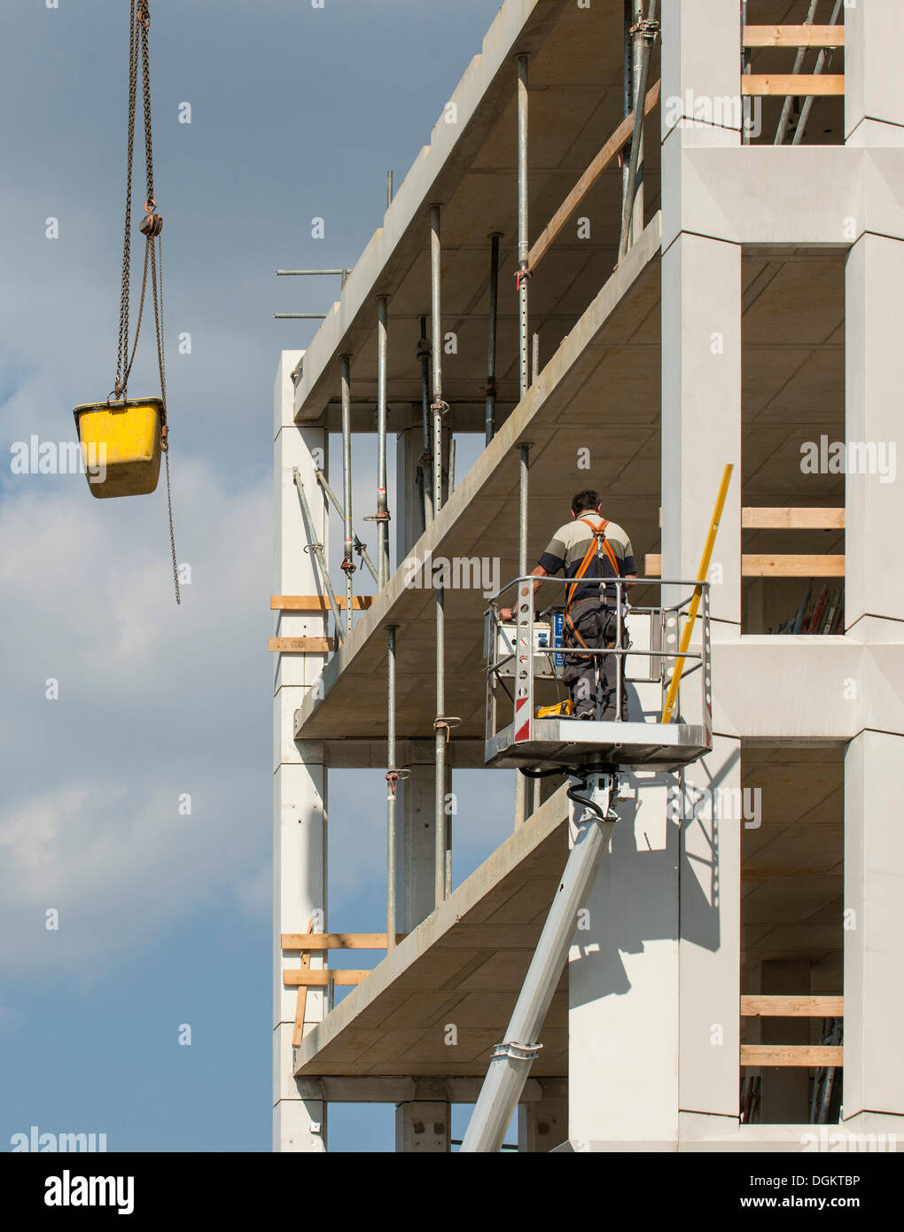 I lavoratori in un ascensore in un cantiere, una cisterna di cemento è abbassata da una gru, sicurezza sul lavoro, PublicGround Foto Stock