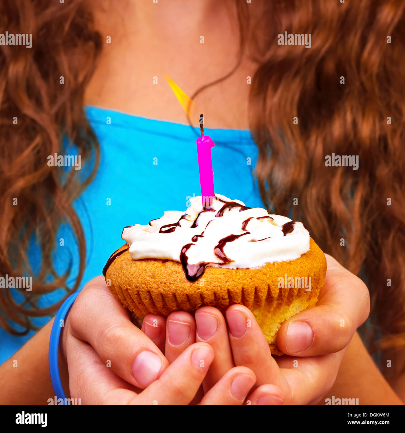 Compleanno ragazza con cupcake festosa nelle mani, esprimere un desiderio, dolce vacanza dessert, divertirsi sulla festa di compleanno, il concetto di felicità Foto Stock