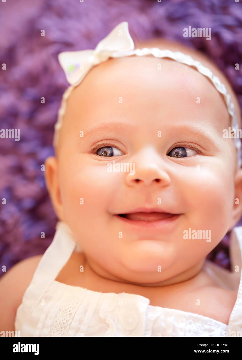 Ritratto di incantevole piccola bambina con i dolci di prua sulla testa, neonato bambino sdraiato a casa, infanzia spensierata felicità, concetto Foto Stock
