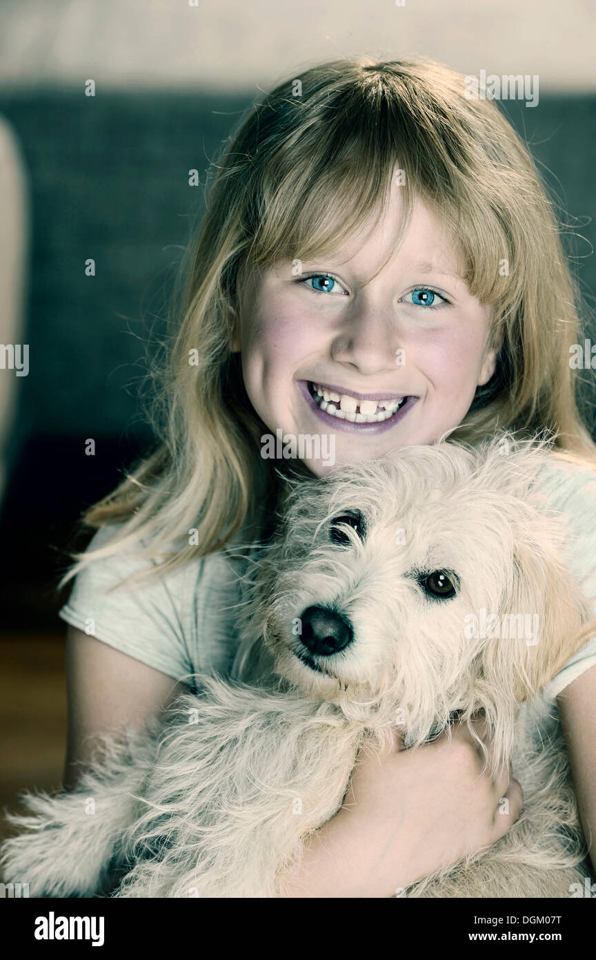 Ragazza, 9, cuddling con un giovane di mixed-cane di razza Foto Stock