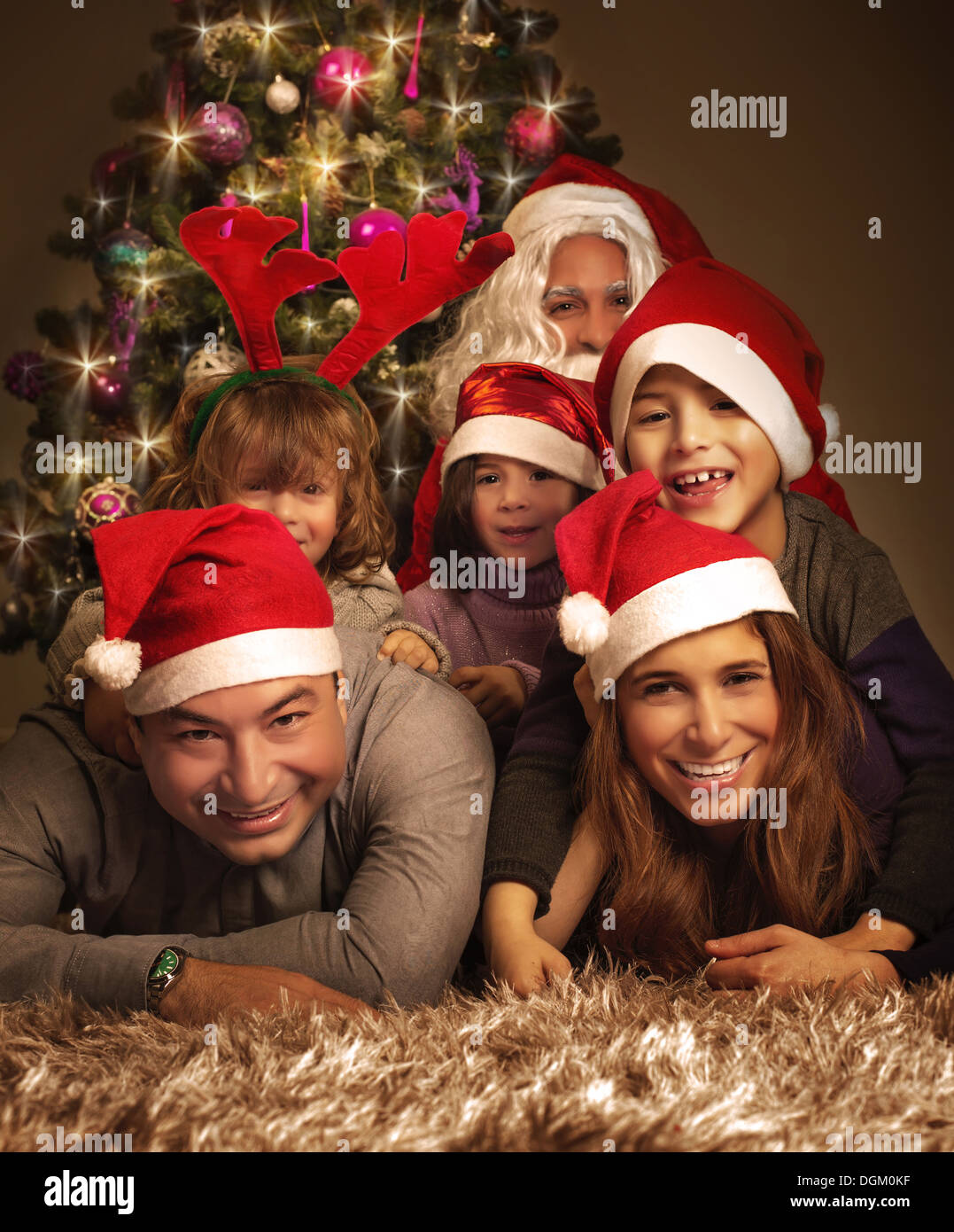 Closeup ritratto della grande famiglia felice con Babbo Natale sdraiati vicino ad albero di Natale, vacanze celebrazione, di gioia e di felicità Foto Stock