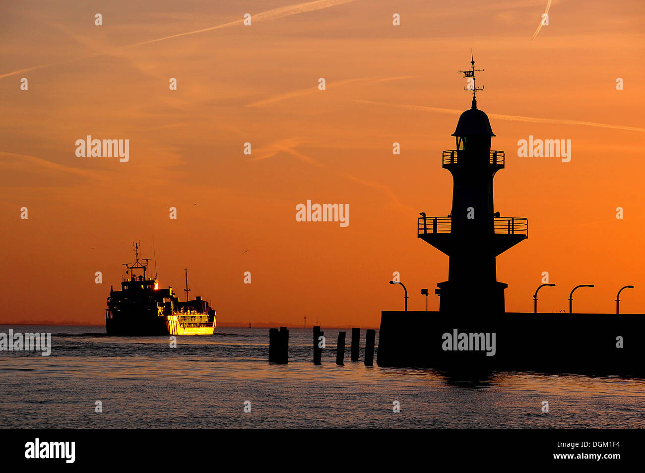 Nave da carico e silhouette di Brunsbuettel mole 1 faro anteriore di un cielo di sera, Brunsbüttel, Schleswig-Holstein Foto Stock