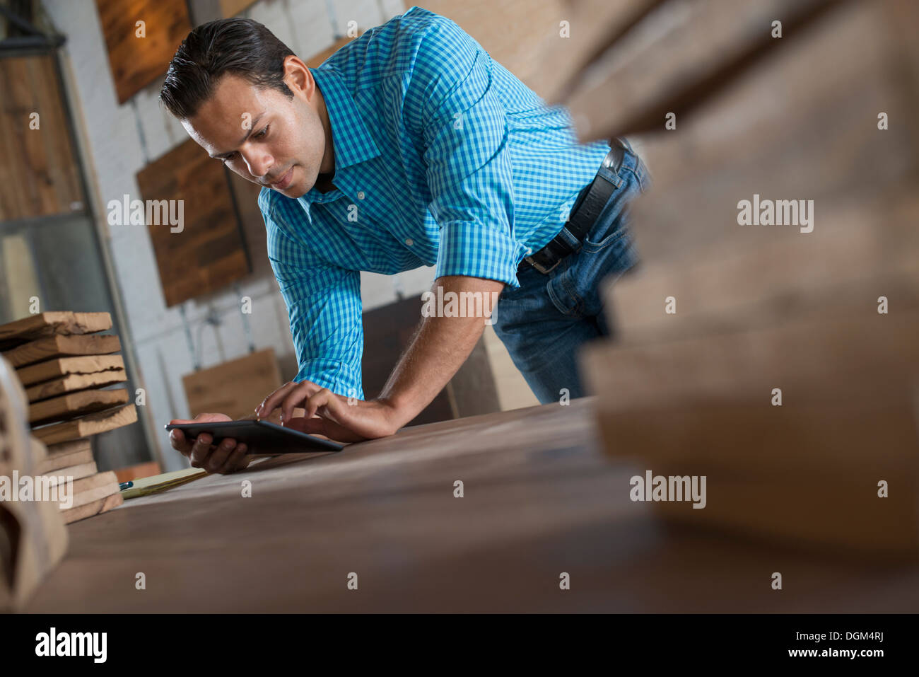 Un giovane uomo in una officina con una tavoletta digitale nel suo lavoro. Foto Stock