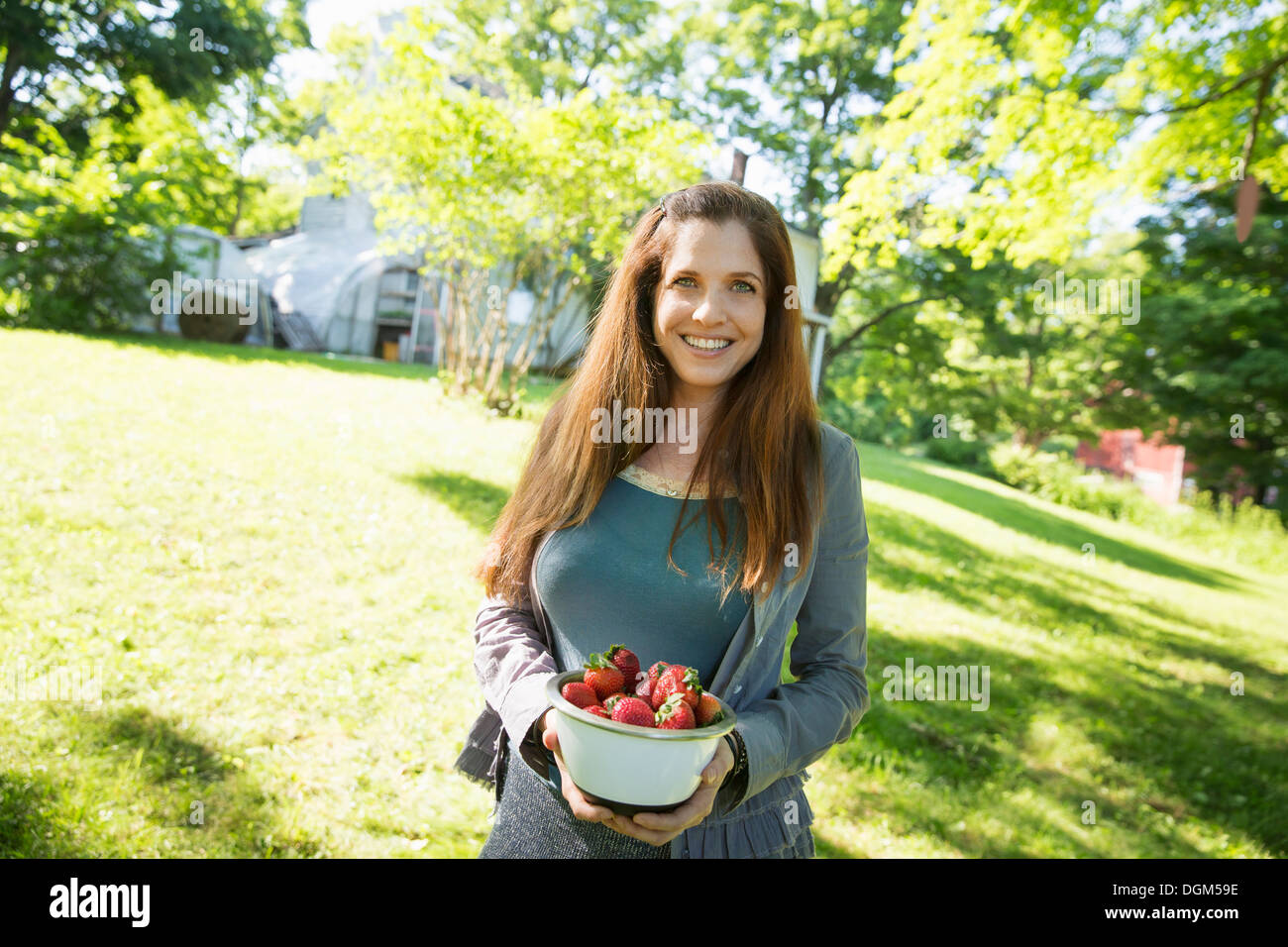 Nella fattoria. Una donna che porta una ciotola di organici raccolti freschi fragole. Foto Stock