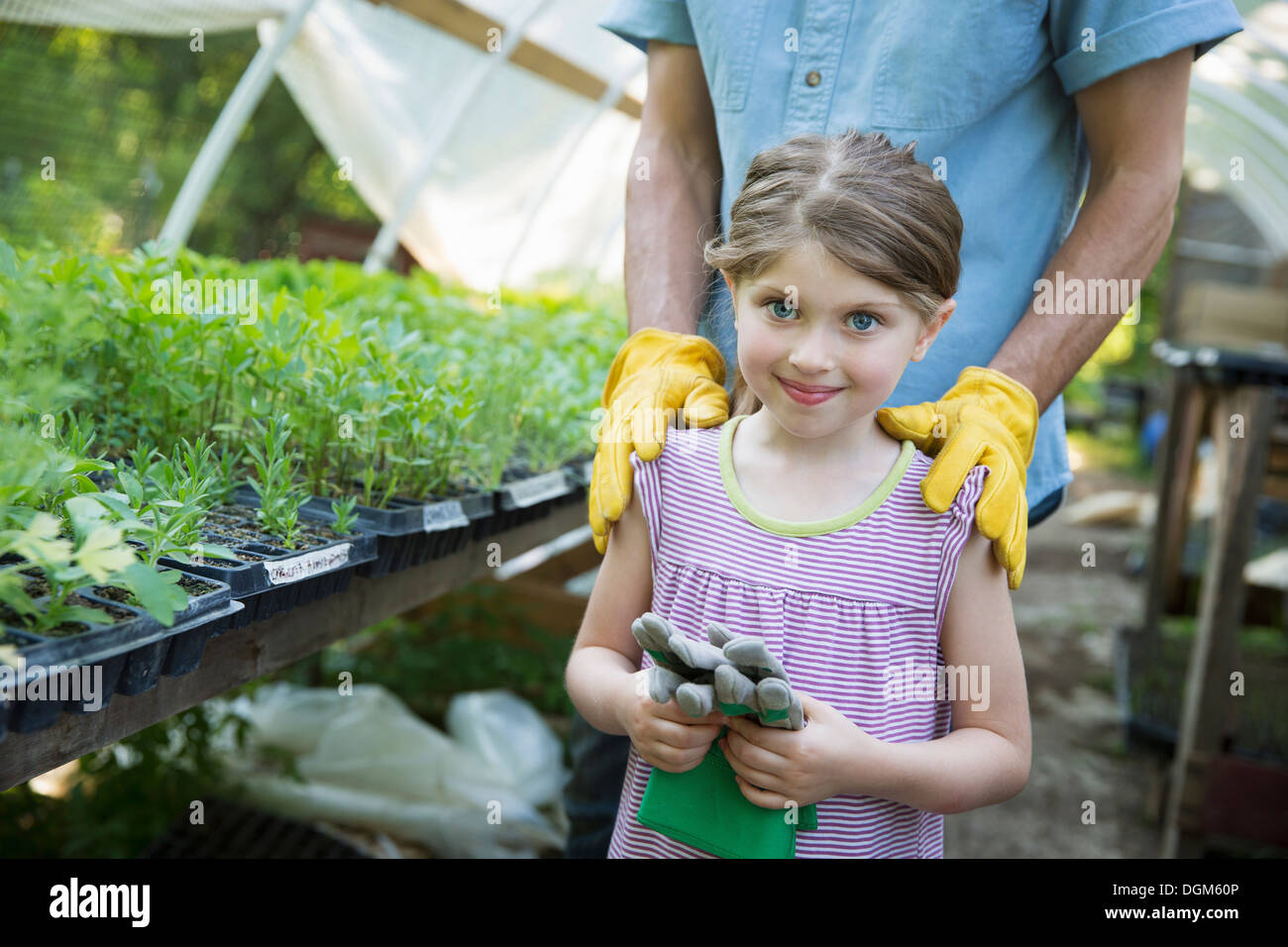 In azienda i figli adulti che lavorano insieme uomo giovane bambino guanti  da giardinaggio in piedi accanto al banco della pianticella di giovani  piante in Foto stock - Alamy