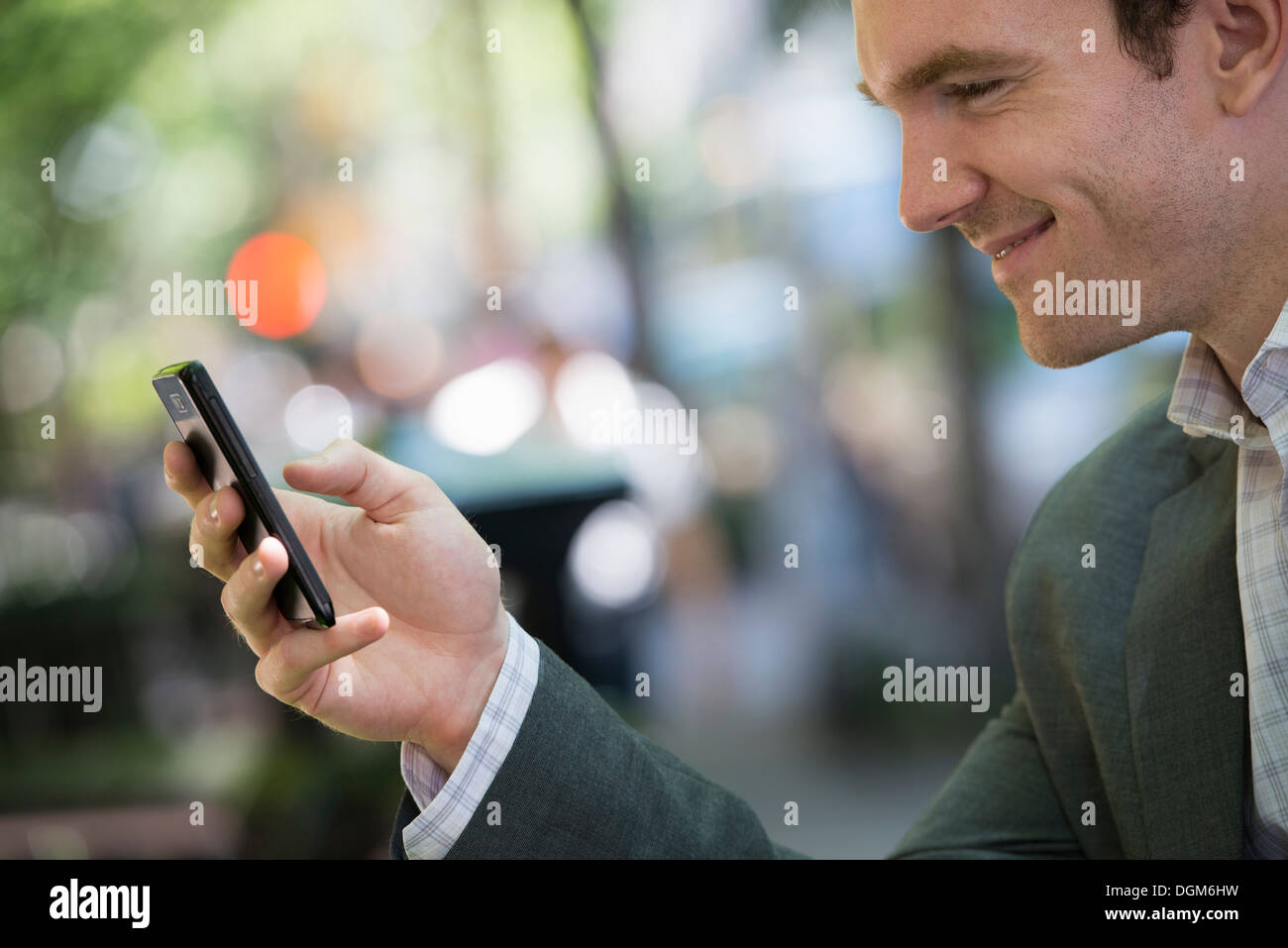 L'estate. Un giovane uomo in un completo grigio. Utilizzando un telefono intelligente. Foto Stock