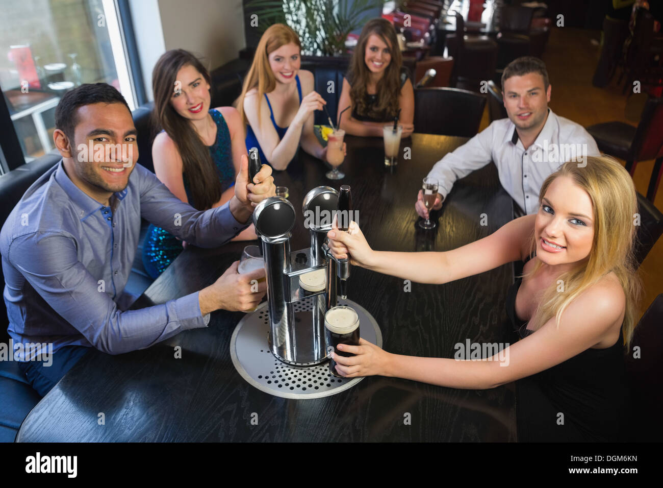 Giovani amici seduti insieme e tirando pinte in un ristorante Foto Stock