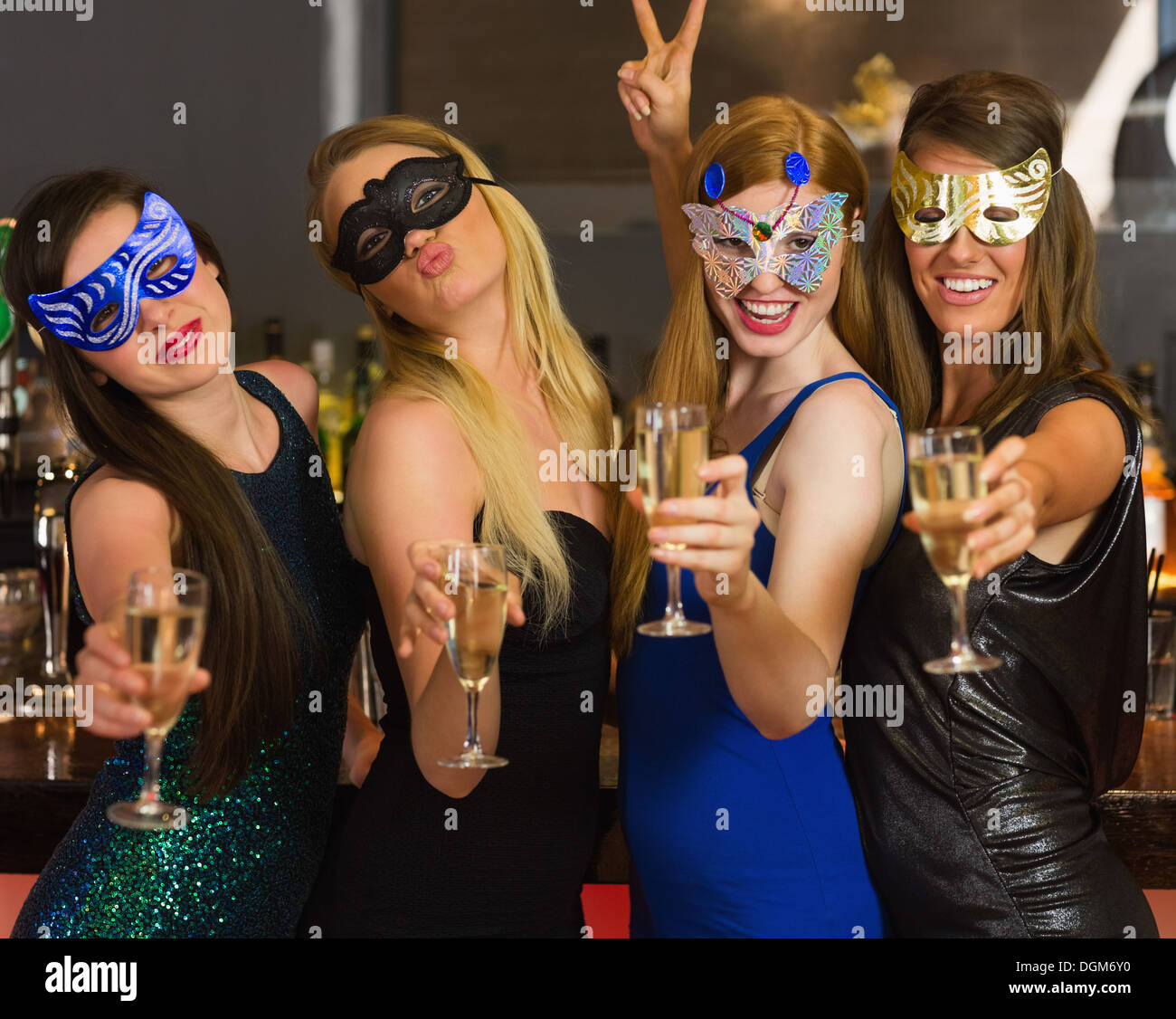 Happy amici indossando maschere che mostra bicchieri da champagne Foto Stock