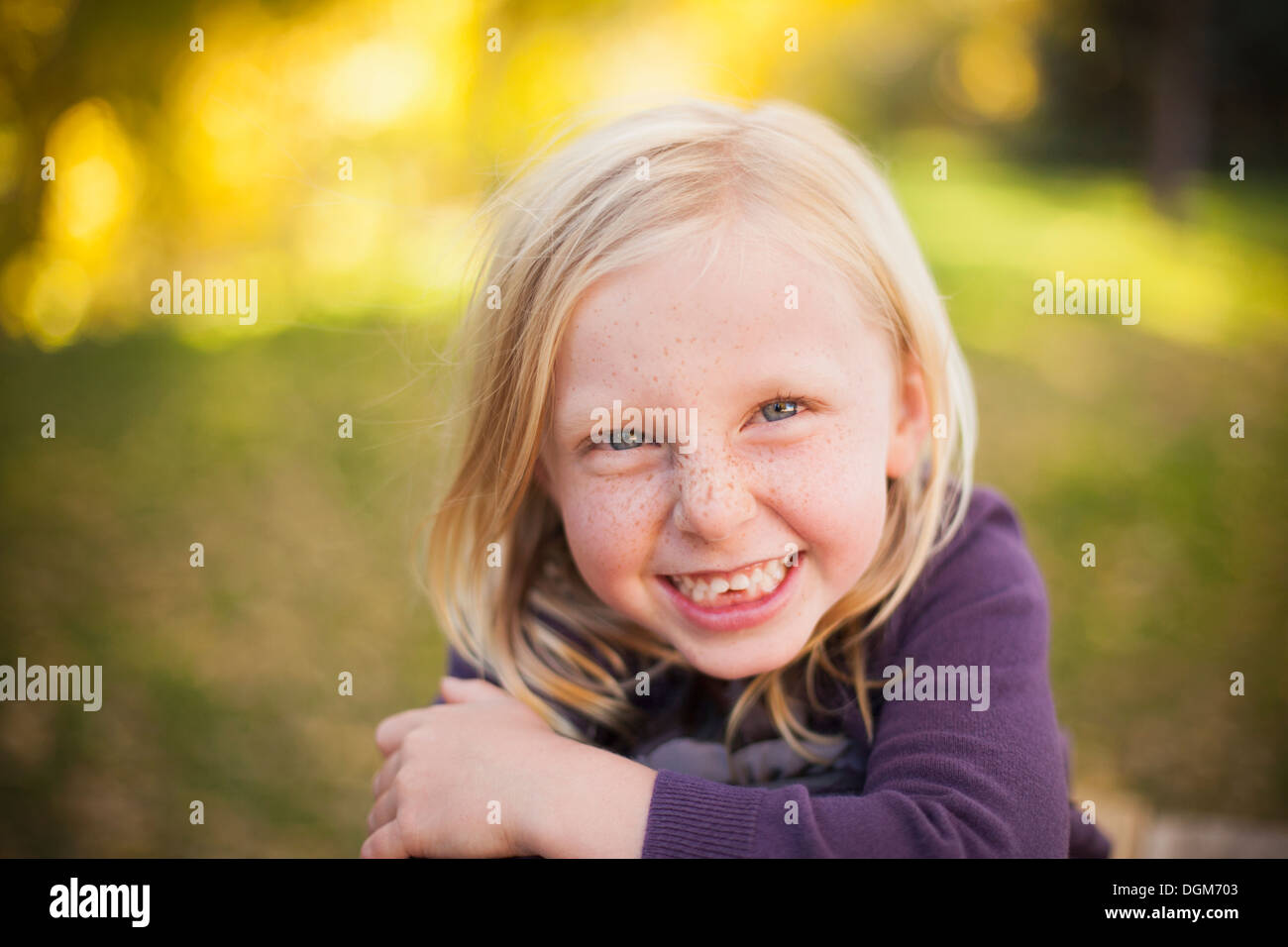 Una ragazza seduta sul prato, sorridente un grande sorriso toothy. Close up. Foto Stock